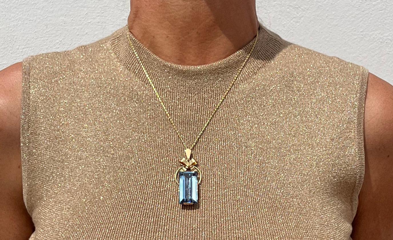 Dieser Anhänger aus 18 Karat Gold und Aquamarin zeigt typische Merkmale dieser Zeit, wie die geraden geometrischen Formen, die glänzende Oberfläche und den Aquamarin im Baguetteschliff. Das Besondere an diesem Anhänger ist der gloriaförmige Kreis