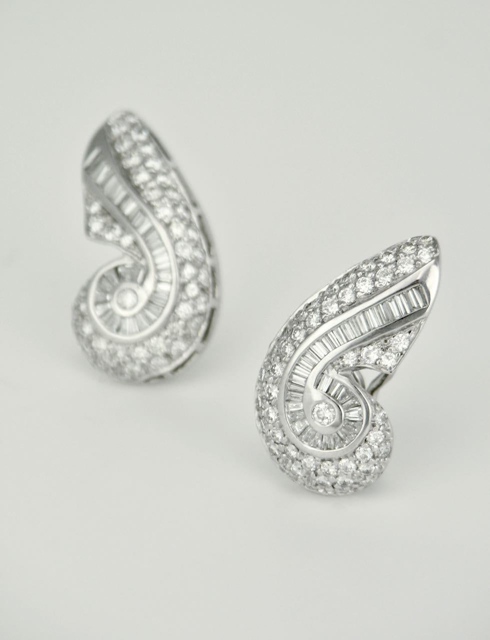 A pair of stunning 18k gold and diamond scroll earrings - each earring consisting of 48 pave set round brilliant cut diamonds set on either side of 35 channel set tapered baguette diamonds in a scroll motif.   The mount has been created in Rhodium