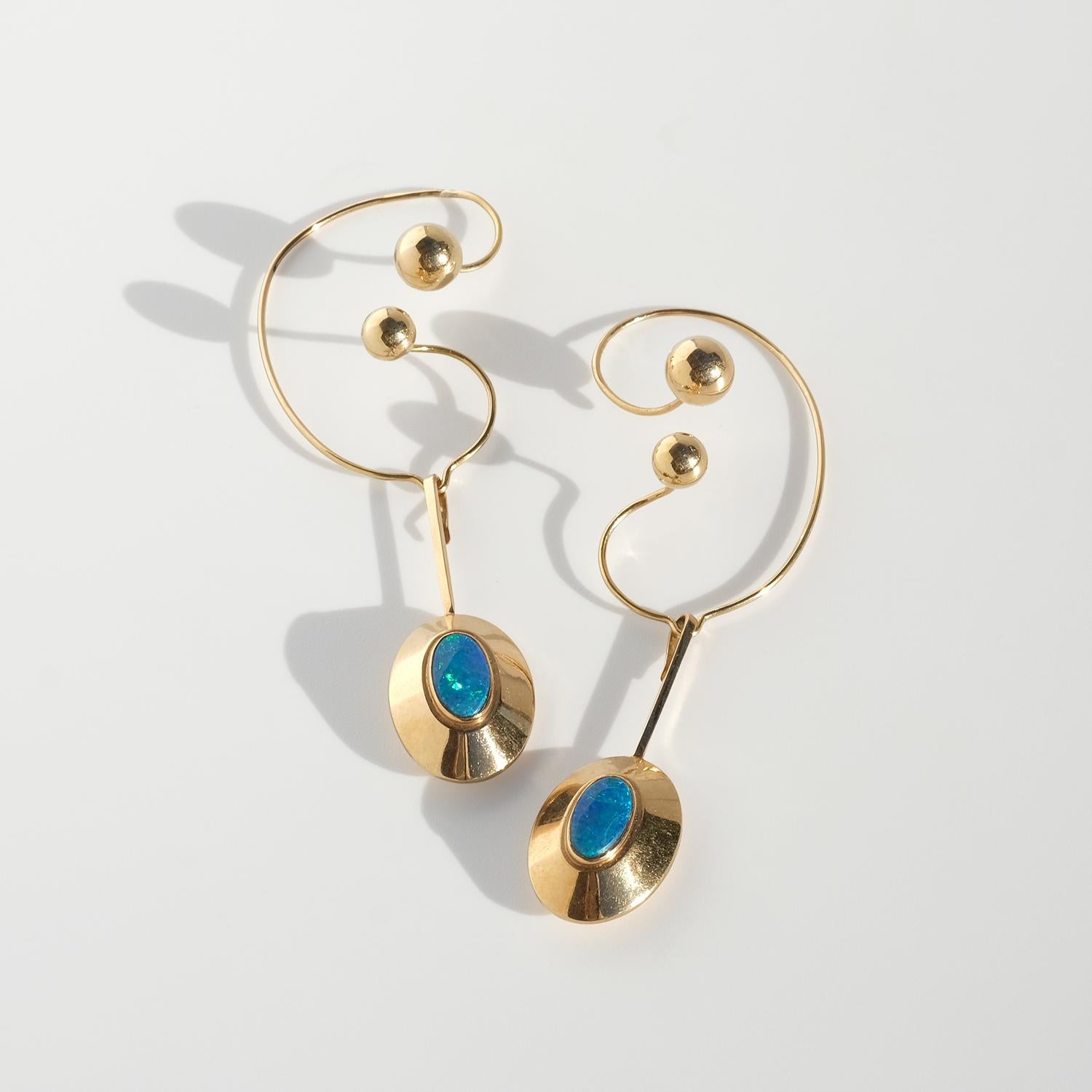 Questi orecchini vintage in oro 18 carati sono caratterizzati da un pendente scultoreo a forma di disco concavo e arrotondato, centrato da un opale ovale cabochon che sembra uno 