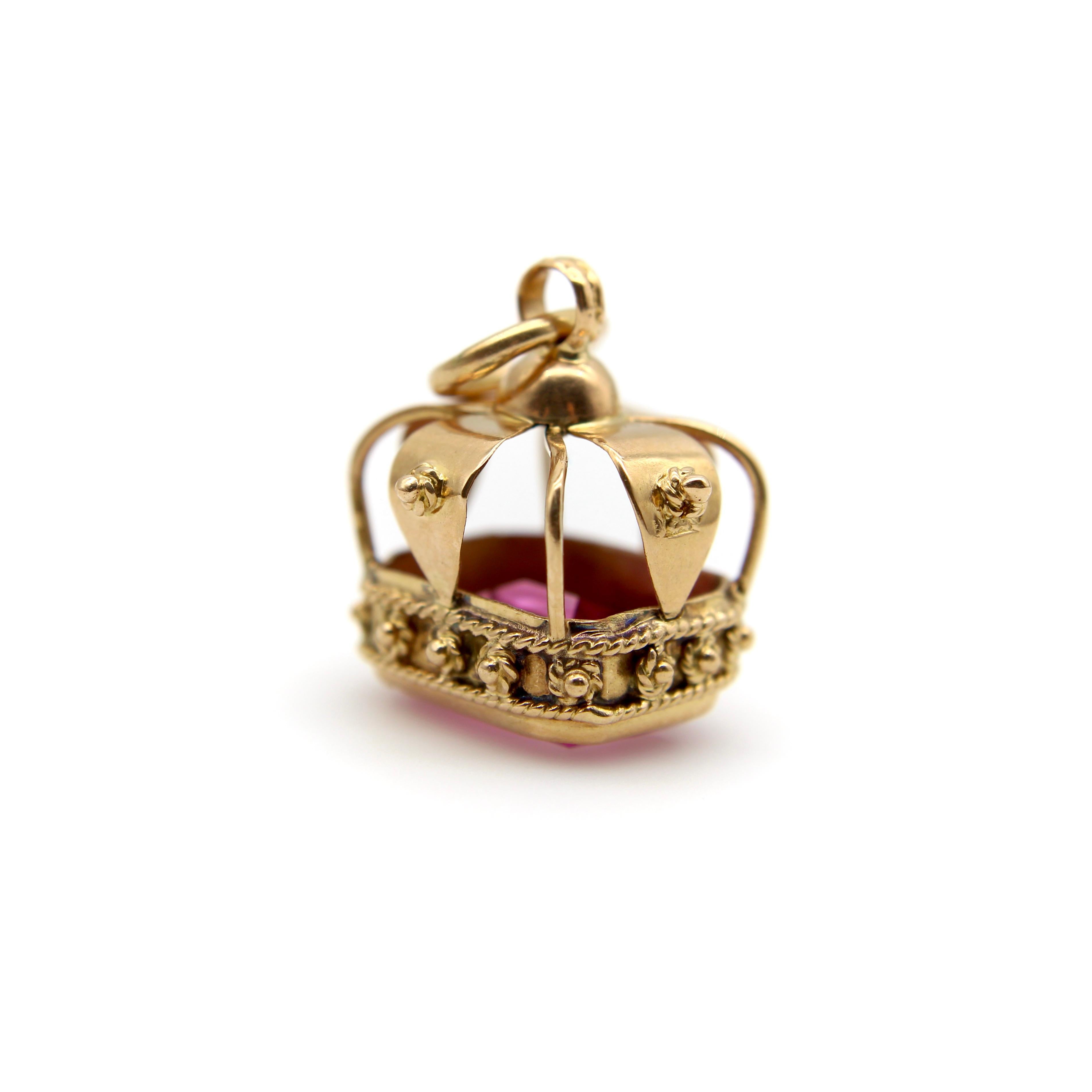 This beautiful 18k gold crown features a large emerald cut synthetic sapphire in a vibrant shade of pink. The crown has lovely granulation and twisted wirework, giving it a regal quality, and the gold has a rosy hue that compliments the sparkling