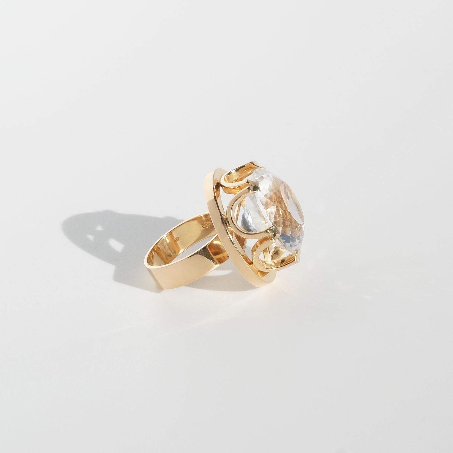 This 18 karat gold ring is adorned by a large, faceted rock crystal. The head of the stone is distinct and it is held by a prominent setting which resembles a king's crown. 

The ring is perfect for the cocktail party and any other social gathering.
