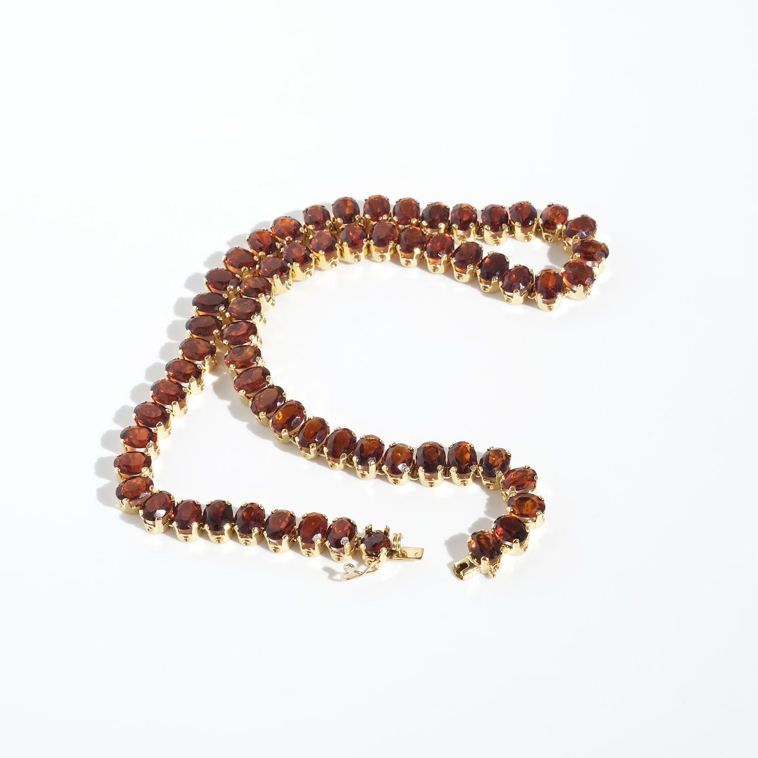 Diese Vintage-Halskette aus 18-karätigem Gold zeichnet sich durch eine auffällige Reihe von 62 facettierten rot-orangen Rauchquarzsteinen aus, die jeweils in zarte Goldzacken gefasst sind, die ihre Brillanz betonen. Die Edelsteine haben einen