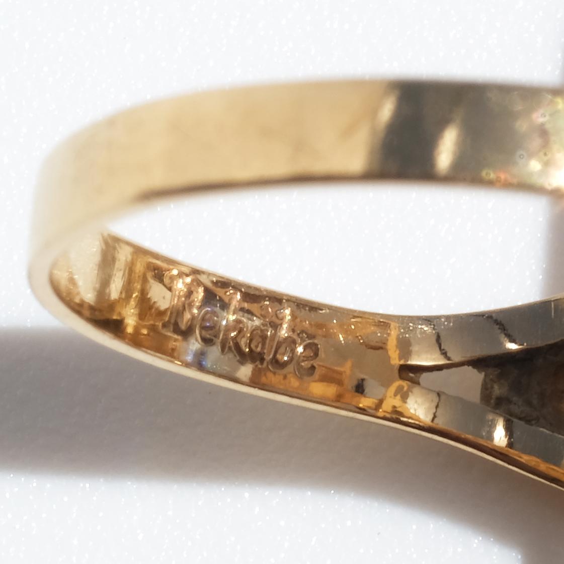 This vintage ring features an 18 karat gold band with a unique, romantic setting design. The setting has intricate openwork patterns surrounding the stone, creating a delicate, airy appearance. The centerpiece is an emerald-cut synthetic sapphire,