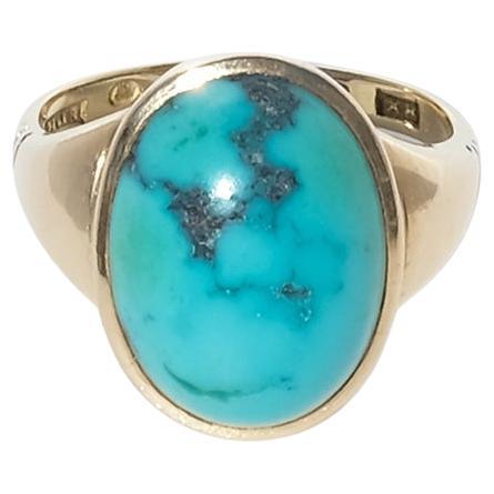 This vintage ring is crafted in 18 karat gold and set with an oval cabochon turquoise, vibrant in tone with a smooth dome and natural dark veining. The stone sits securely in a clean bezel that frames its organic beauty. The slender shank is subtly