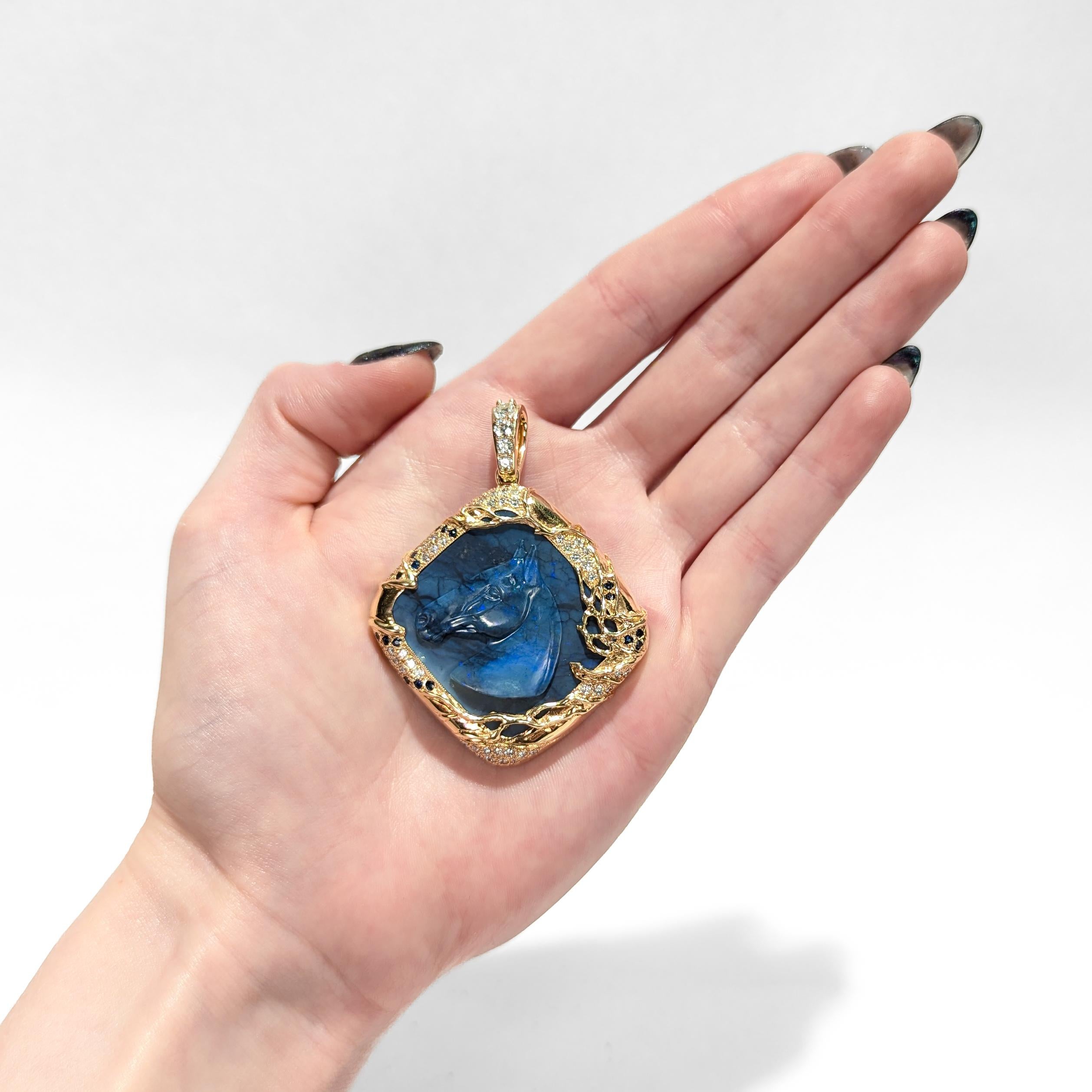 A fine vintage gold, opal, sapphire, and diamond pendant.

In 18 karat yellow gold.

With a large ca. 44.00± ct carved cushion shape black opal carved with a horse's head in profile. 

The cabochon set within a gold mount with organic decoration