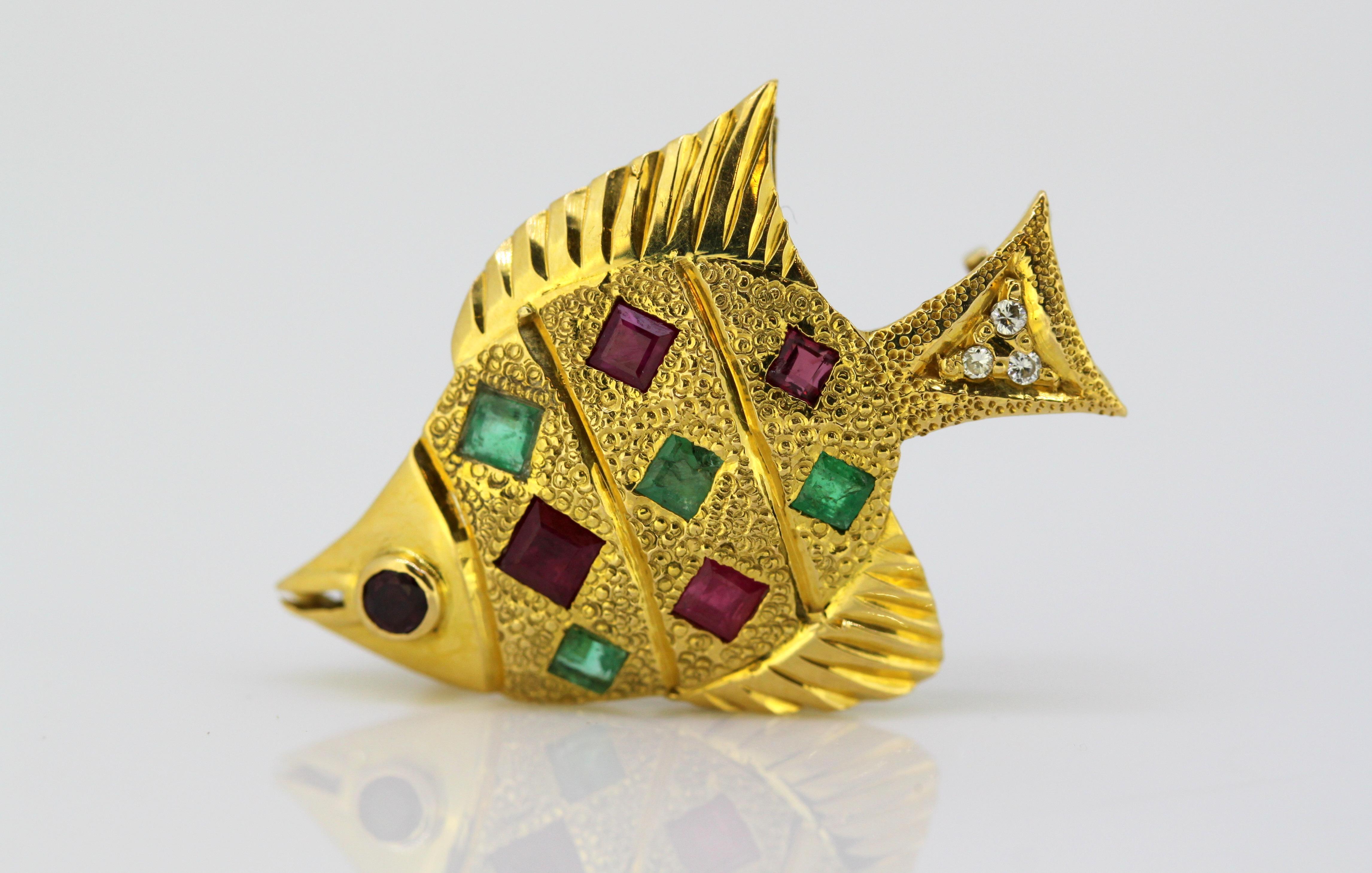 Vintage 18k gold brooch/pendant in the shape of a fish, decorated with emeralds, rubies, and diamonds.
Circa 1970's
Hallmarked 750.

Approx Dimensions - 
Size : 2.7 x 2 x 1 cm
Weight : 5 grams

Emerald - 
Cut : Square
Number of stones : 4
Total size