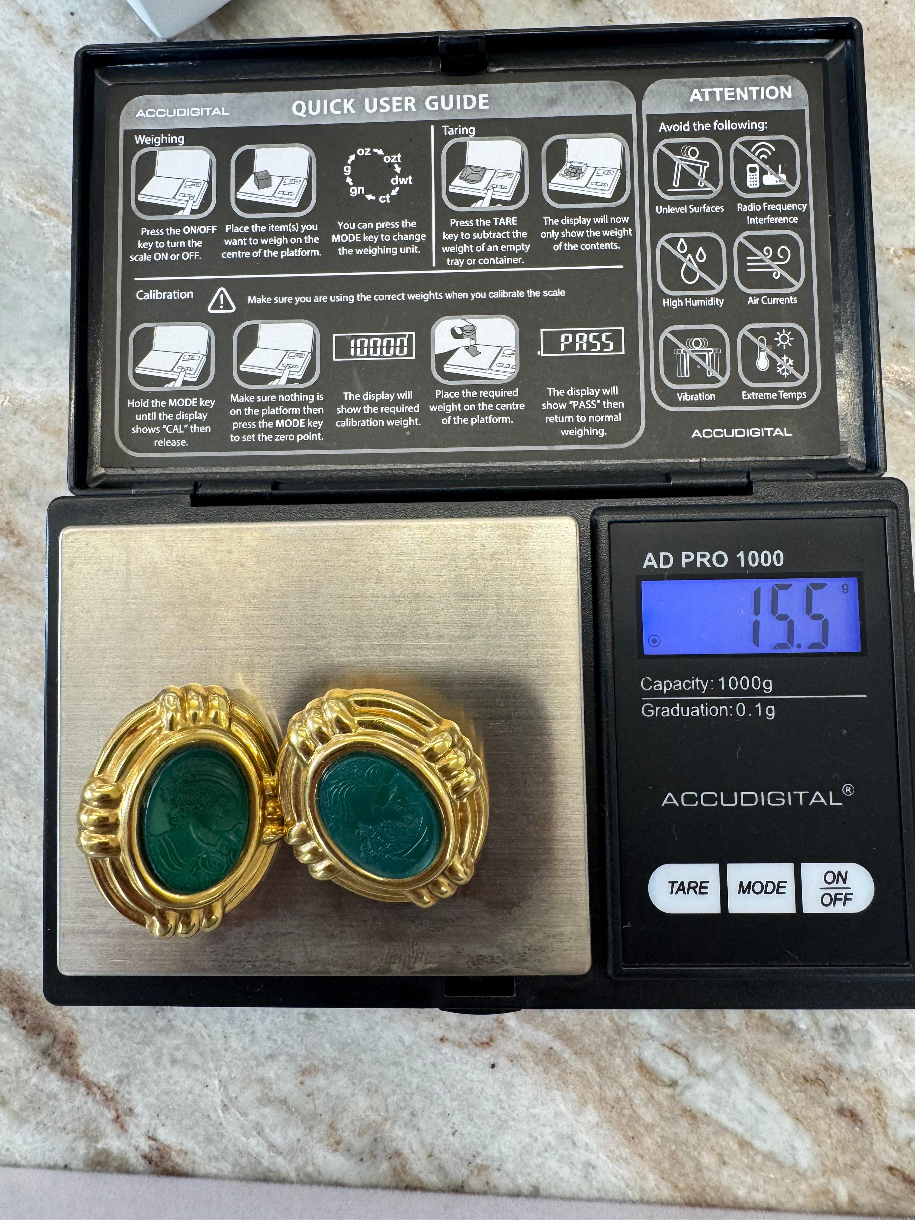 A bold and elegant pair of vintage earrings featuring finely carved green hardstone intaglios set in rich 18K yellow gold. Each oval-shaped hardstone is intricately engraved with a classical female profile and framed in a ribbed gold bezel setting.