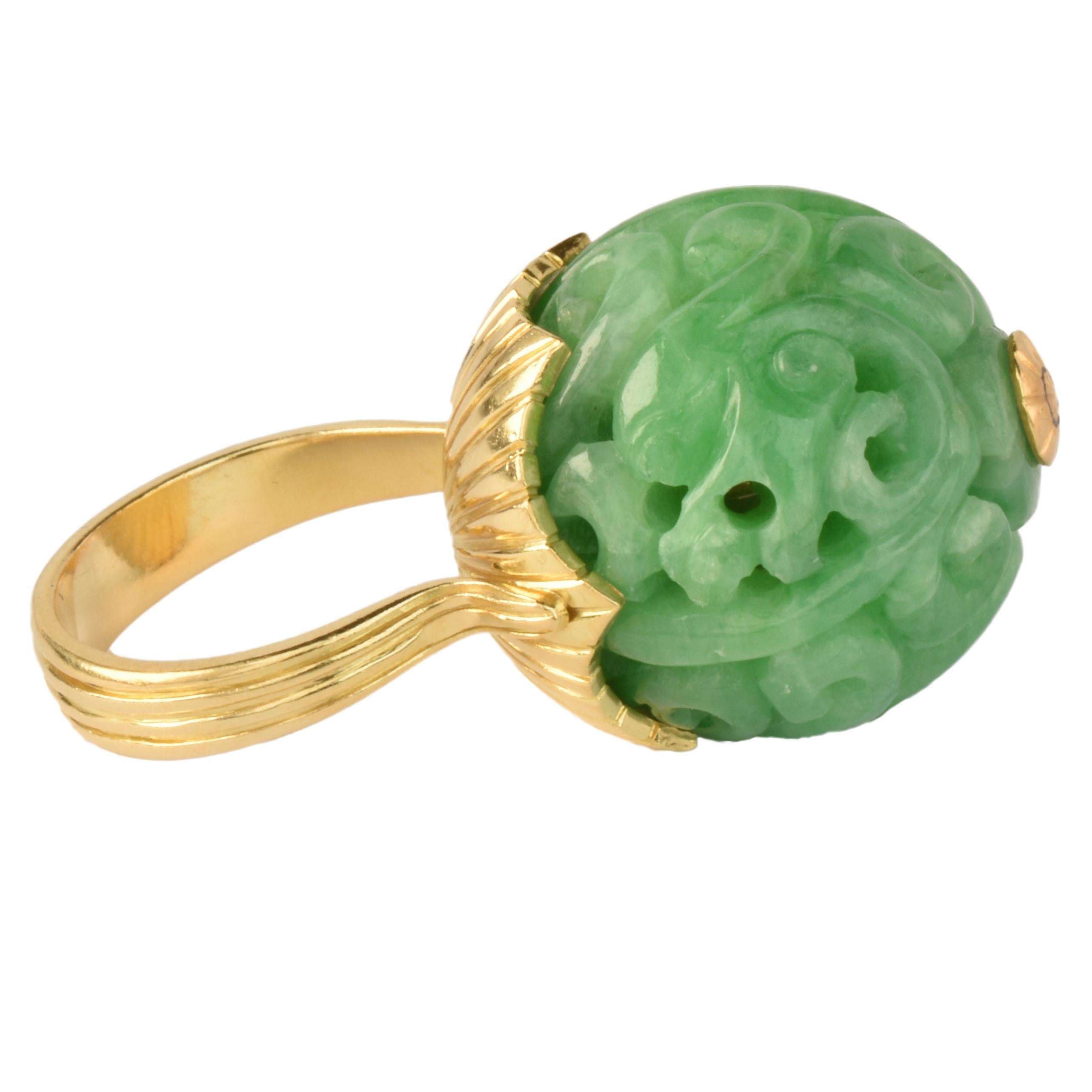 A bold & unusual 1970s ring. Fashioned from 18k yellow gold with reeded texture supporting a carved jadeite bead.