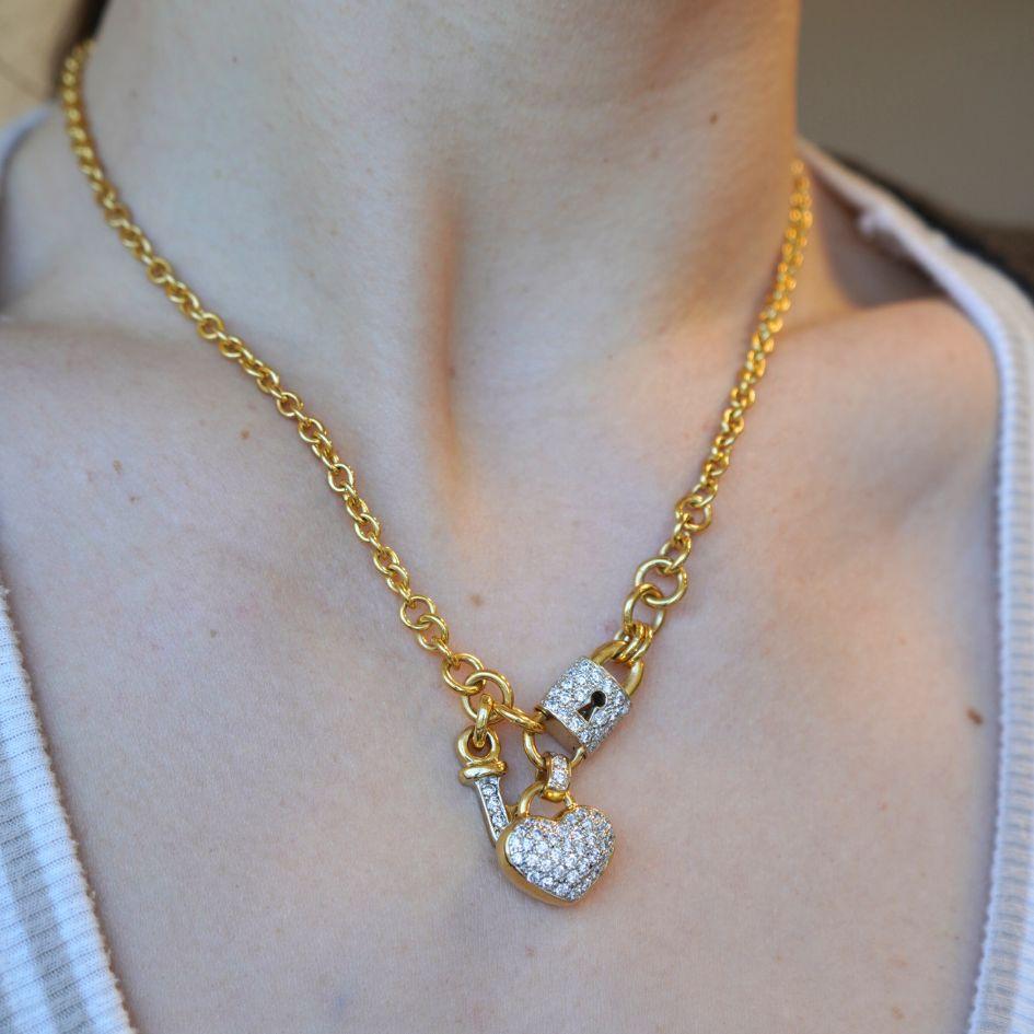 Diese Vintage-Halskette aus 18 Karat Gelbgold besteht aus einem symbolischen Trio aus Herz, Schloss und Schlüssel, die jeweils mit Diamanten in Pavé besetzt sind. Das Herz und das Schloss sind mit aufeinander abgestimmten Pavé-Diamanten versehen,