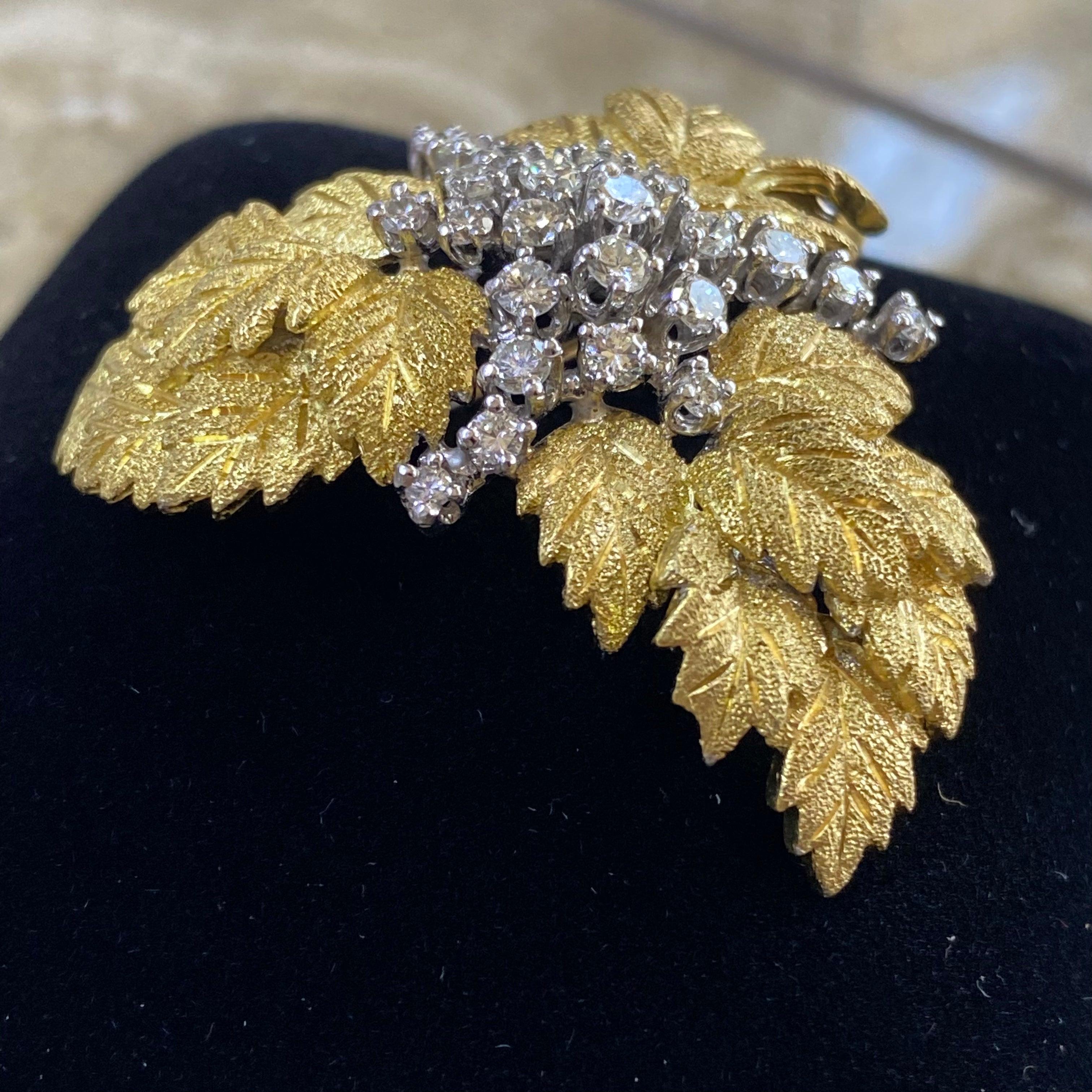 Crafted in 18K gold, the brooch features a domed cluster of textured finished yellow gold leaves topped with ribbons of diamonds set in white gold. The brooch has a couple of gold loops on the back to attach it to a chain to wear it as a pendant.