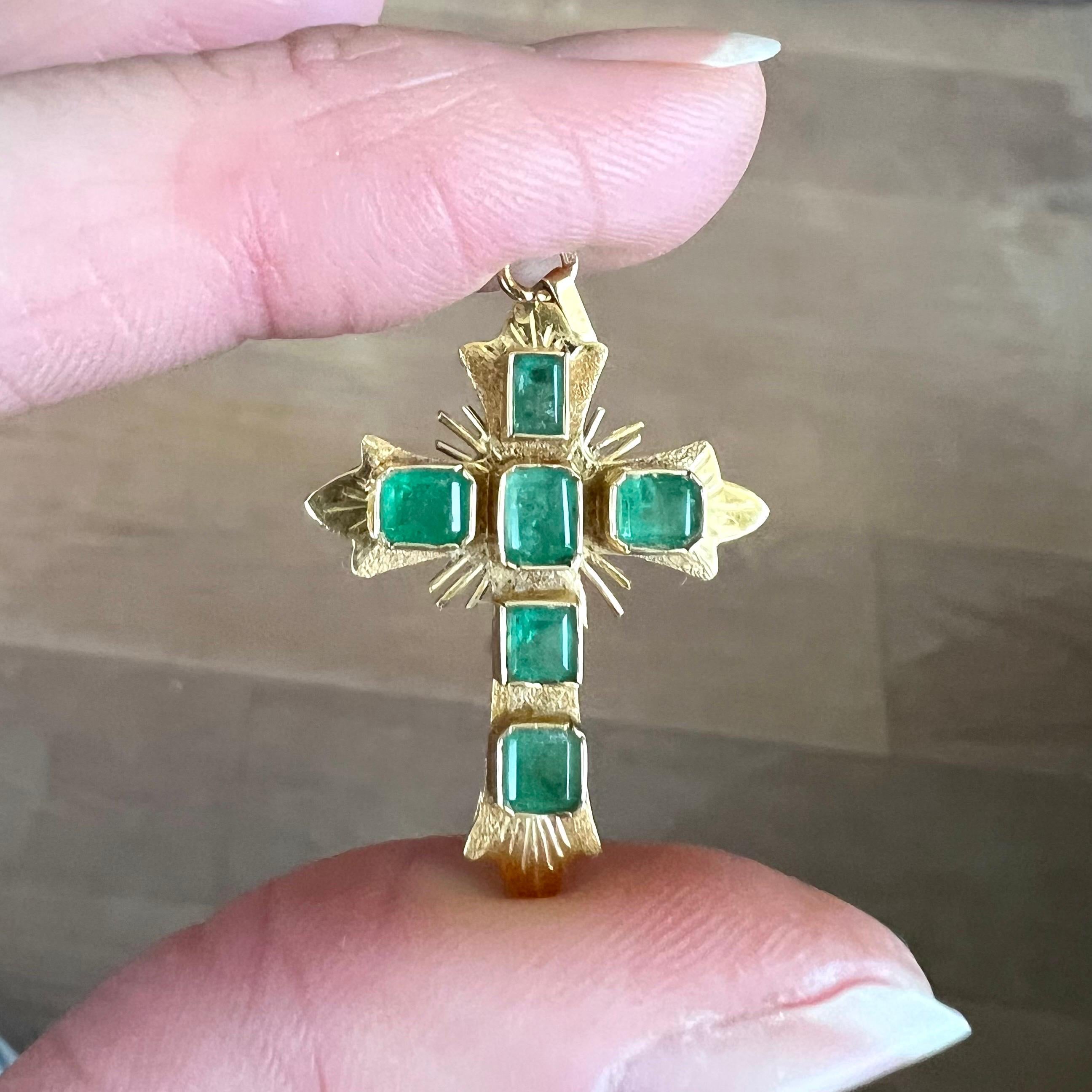 A wonderful ornate vintage 18 karat yellow gold emerald cross pendant. The pendant is beautifully made, encrusted with six individual emerald cut Colombian emerald gemstones. The bezel set emeralds are set in a gold satin finish and divine rays