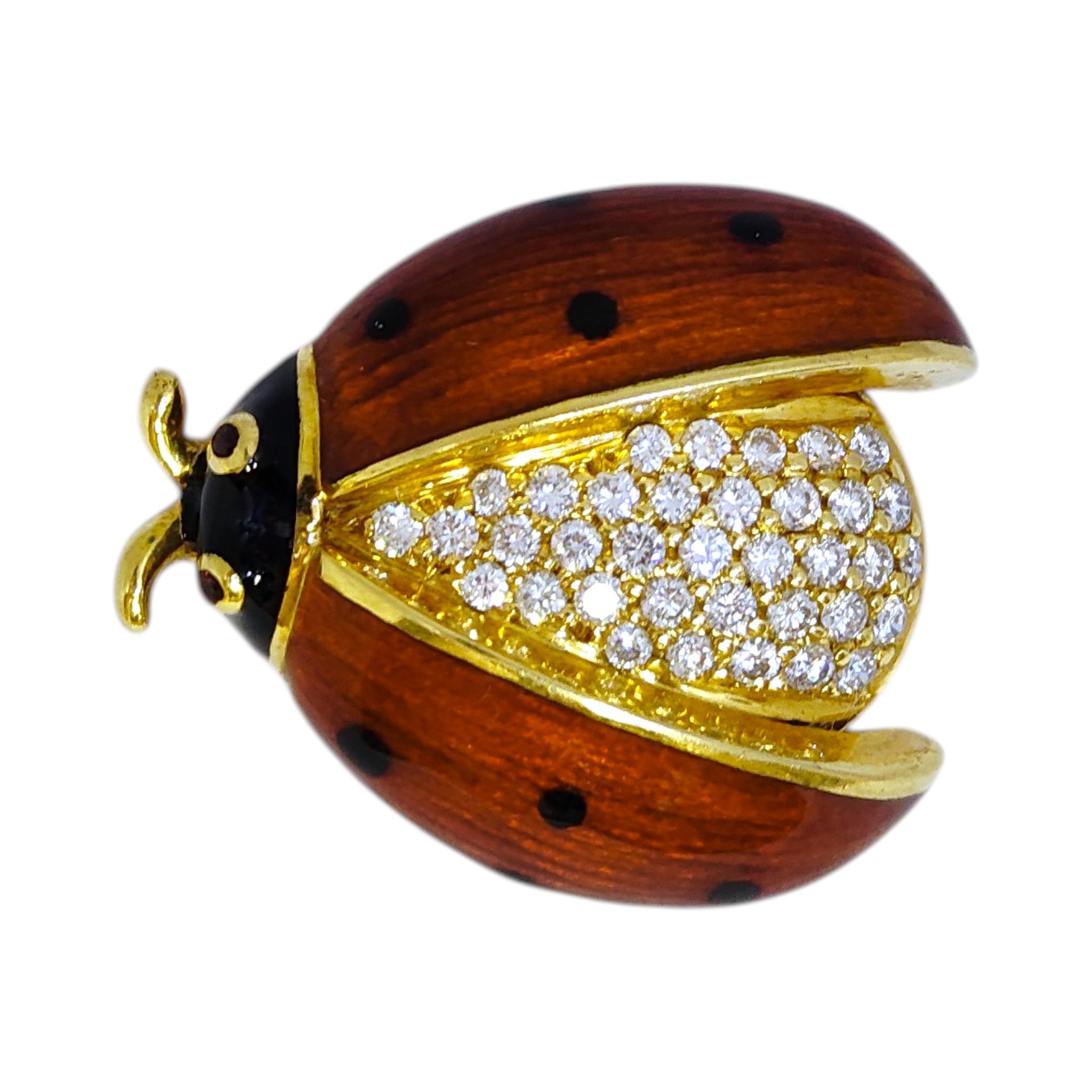 Vintage 18K yellow gold brooch in a ladybug design. The body is encrusted with diamonds and the wings are decorated with rich brownish red enamel with black spots. Purplish red garnet eyes.  Polished gold accents outline the wings and