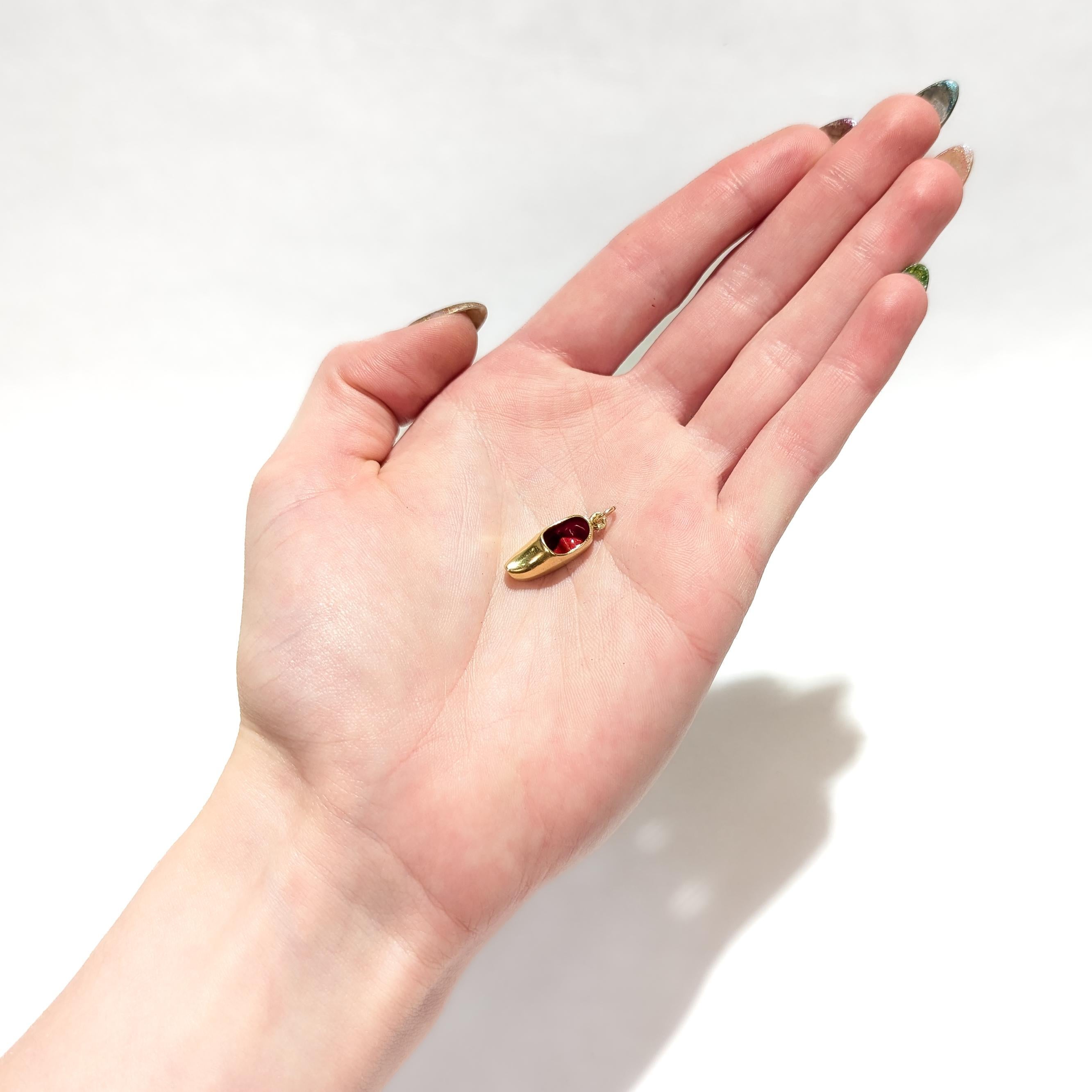 A fine vintage figural gold charm.

In 18 karat yellow gold.

In the form of a wooden clog (like the traditional Dutch klompen) with red enamel accent to the interior.

With an integral bail and jump ring to the heel.

Simply a wonderful