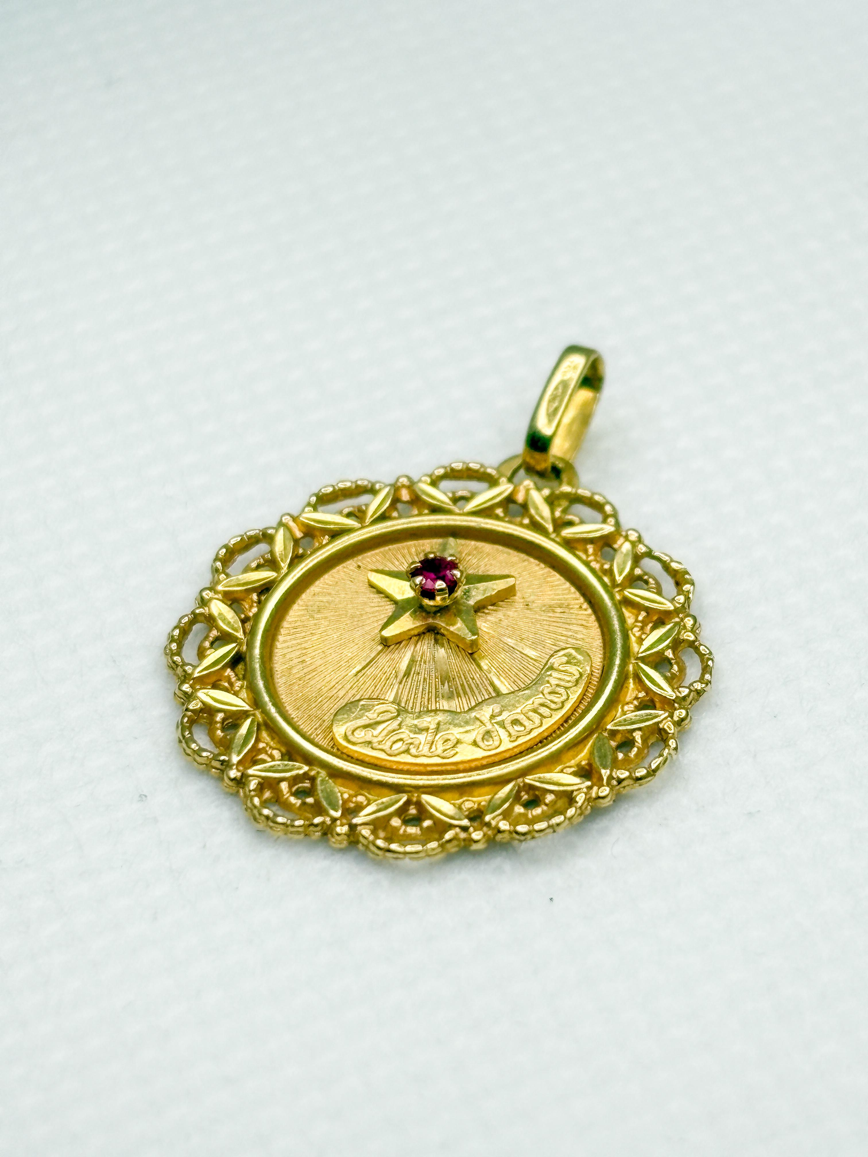 Charmant pendentif Étoile d'Amour vintage en or jaune 18k du joaillier lyonnais Perroud, présentant un motif étoilé serti d'un petit rubis synthétique d'environ 1,5 mm. Les rayons finement gravés rayonnent de la pierre et illuminent l'inscription