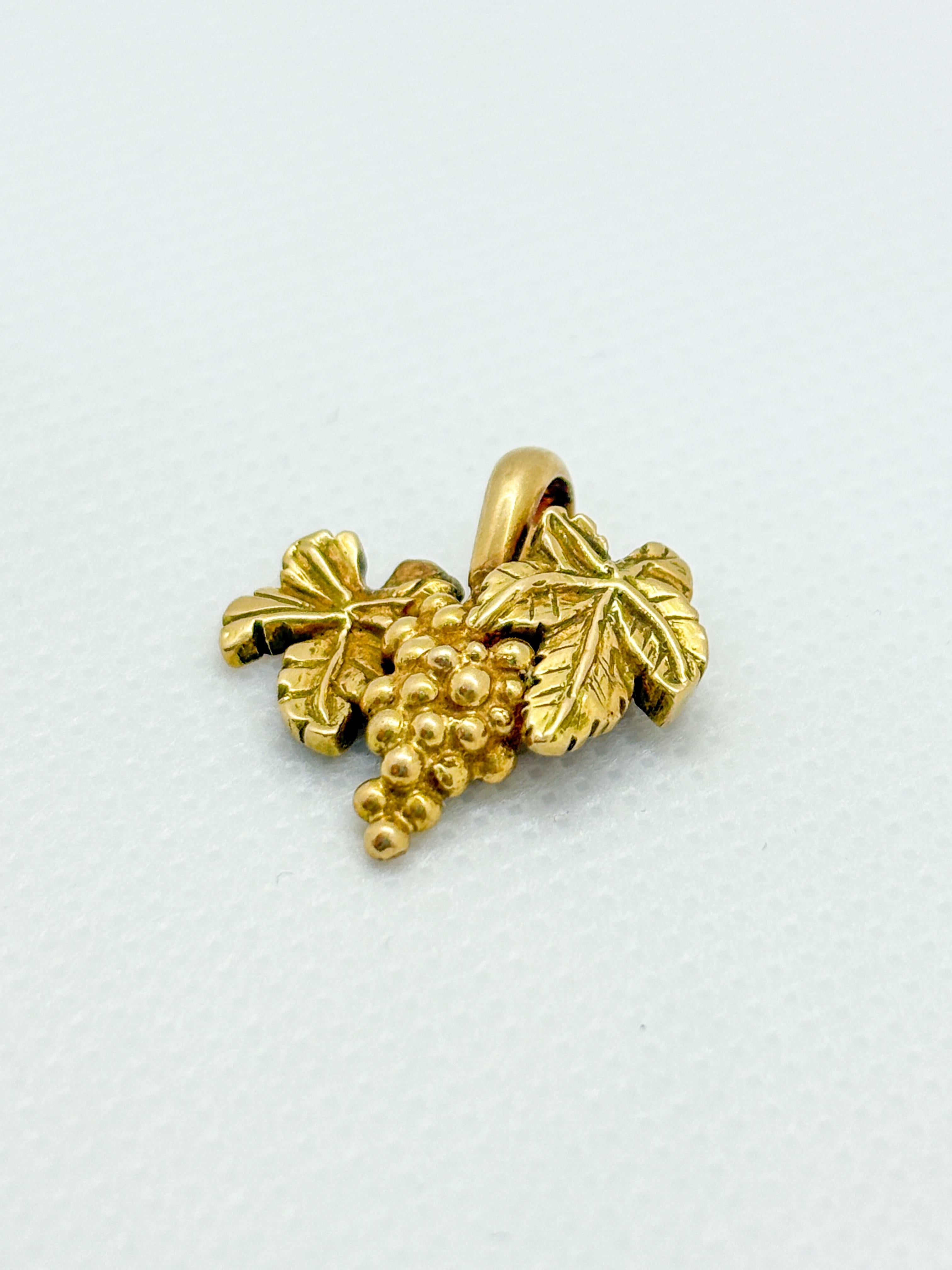 Affascinante ciondolo vintage in oro giallo 18k a forma di grappolo d'uva con foglie di vite finemente dettagliate. Realizzato a mano da un artigiano francese e recante il marchio di fabbrica e il marchio della testa dell'aquila, questo solido pezzo
