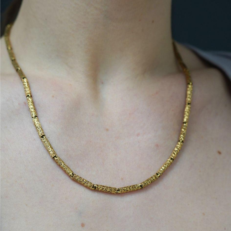 Ce collier vintage en or 18 carats martelé, datant des années 1970, présente un design texturé distinctif. Le collier est composé de maillons allongés en forme de tonneau, chacun gravé avec des lignes organiques qui ressemblent à l'écorce d'un