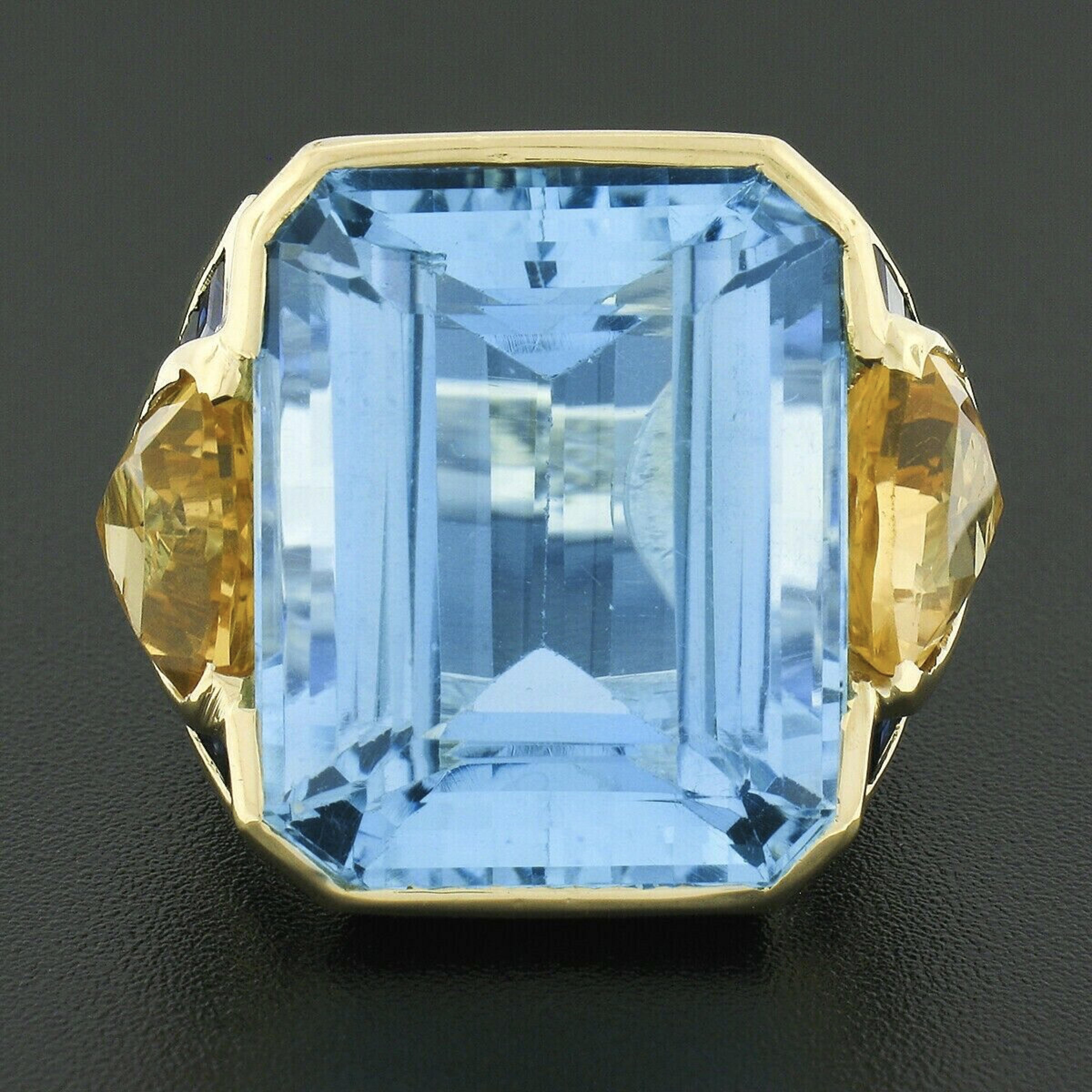 This absolutely breathtaking vintage statement ring was crafted in solid 18k yellow gold and features a HUGE natural genuine blue topaz solitaire neatly channel set at its center. This very fine stone has an emerald cut and displays the most