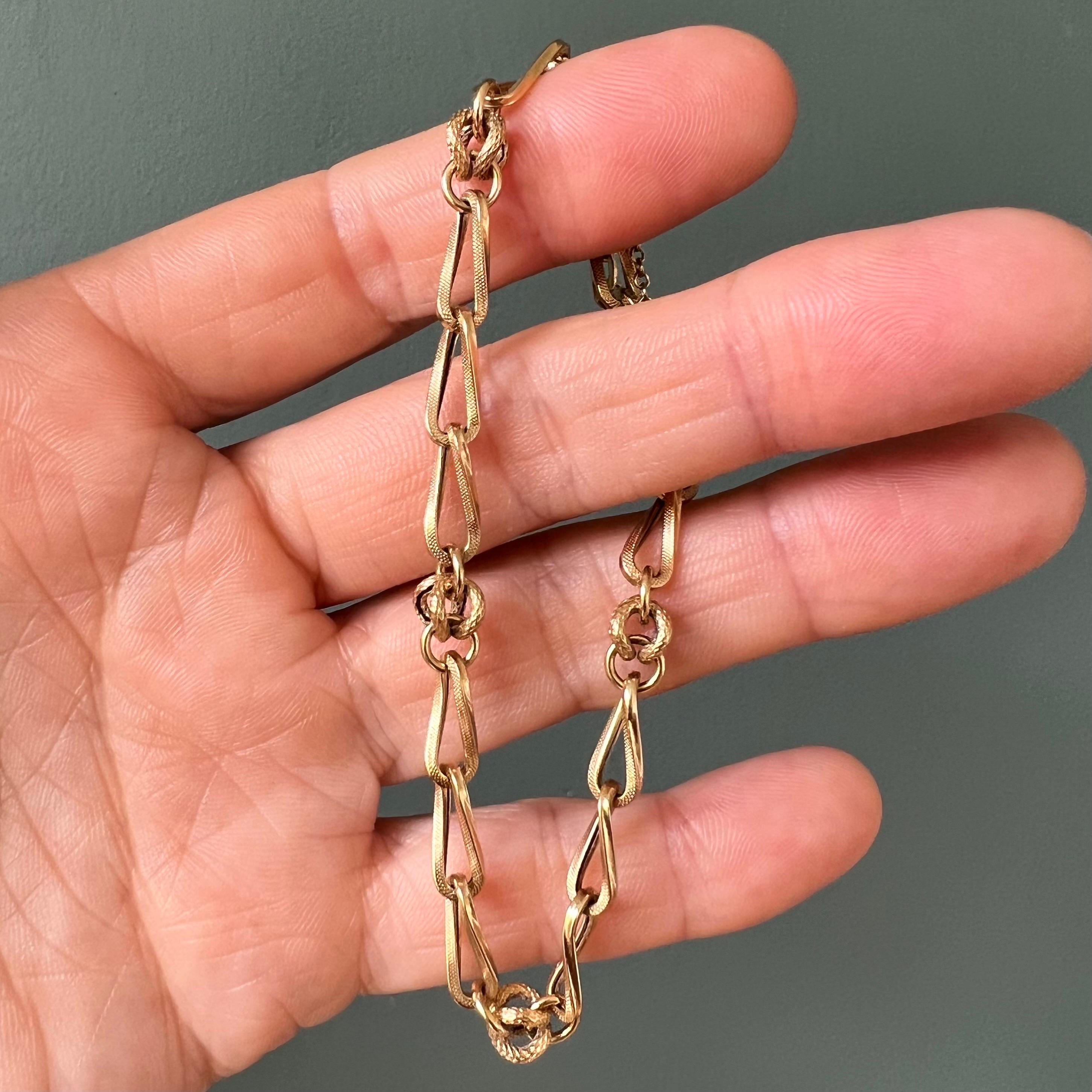 Ce bracelet vintage en chaîne en or 18 carats est une pièce magnifiquement réalisée qui respire l'élégance intemporelle. Le bracelet présente des maillons de chaîne légèrement torsadés qui alternent avec des nœuds dorés complexes, créant ainsi un