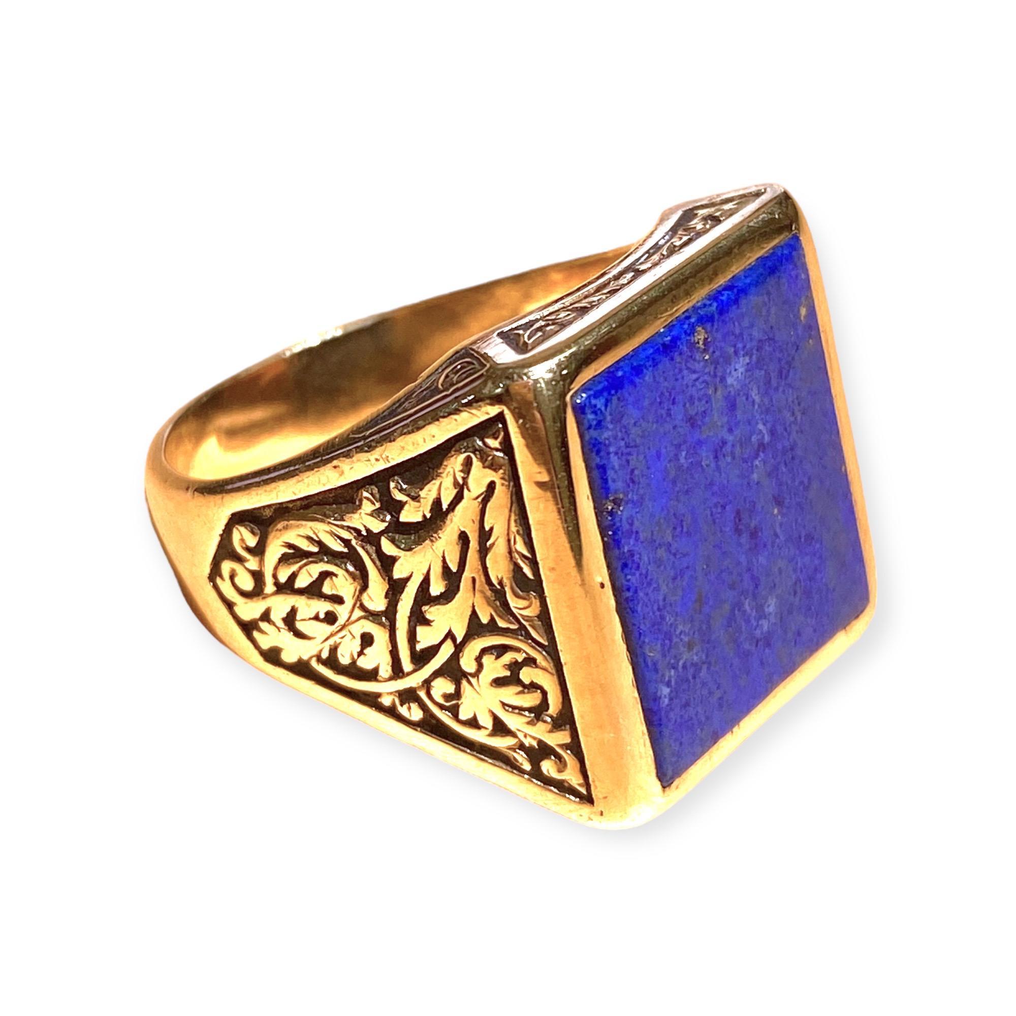 Crafted in 18K yellow gold, the ring features a large rectangular shape lapis lazuli set within a gold bezel, supported by elaborately decorated tapering shoulders, completed by a 4.90 millimeter wide band. 
Measurements:
Front: 18.5 mm H x 17 mm