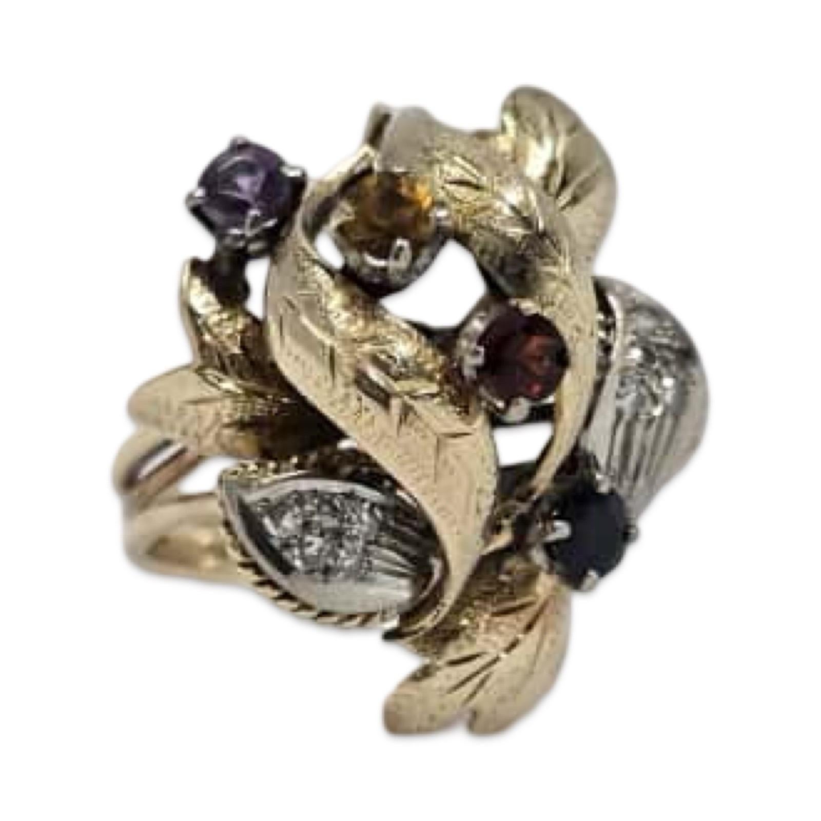 Un sorprendente anello floreale vintage in oro giallo 18 carati con un vibrante mix di gemme naturali e diamanti, splendidamente disposti tra foglie d'oro strutturate. Il design floreale scultoreo mette in mostra quattro gemme rotonde - tra cui