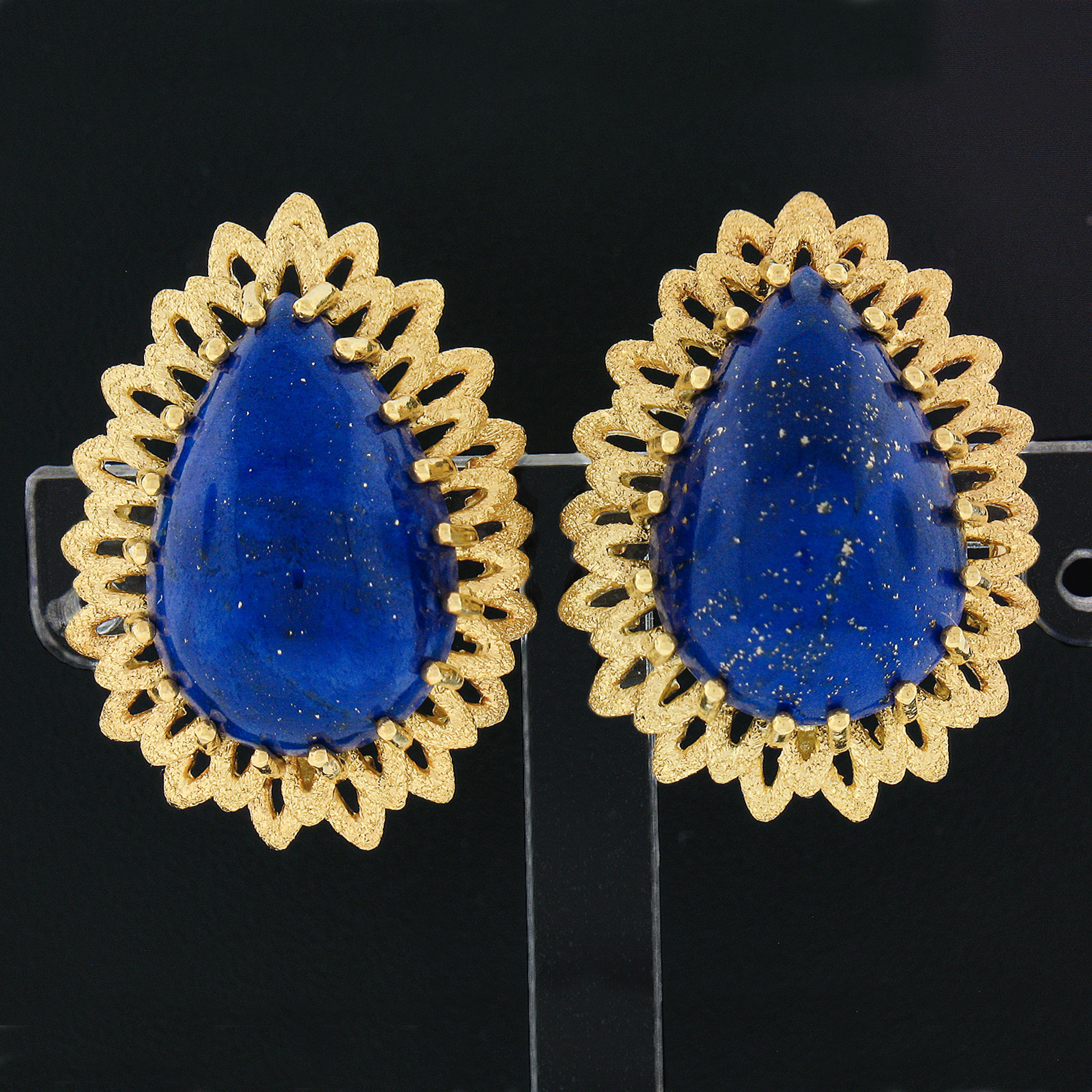 These beautiful vintage earrings are crafted in solid 18k yellow gold and feature a pair of absolutely gorgeous lapis stones. These large lapis are pear cabochon cut and are multi-prong set at the center of an elegantly layered and flared open work