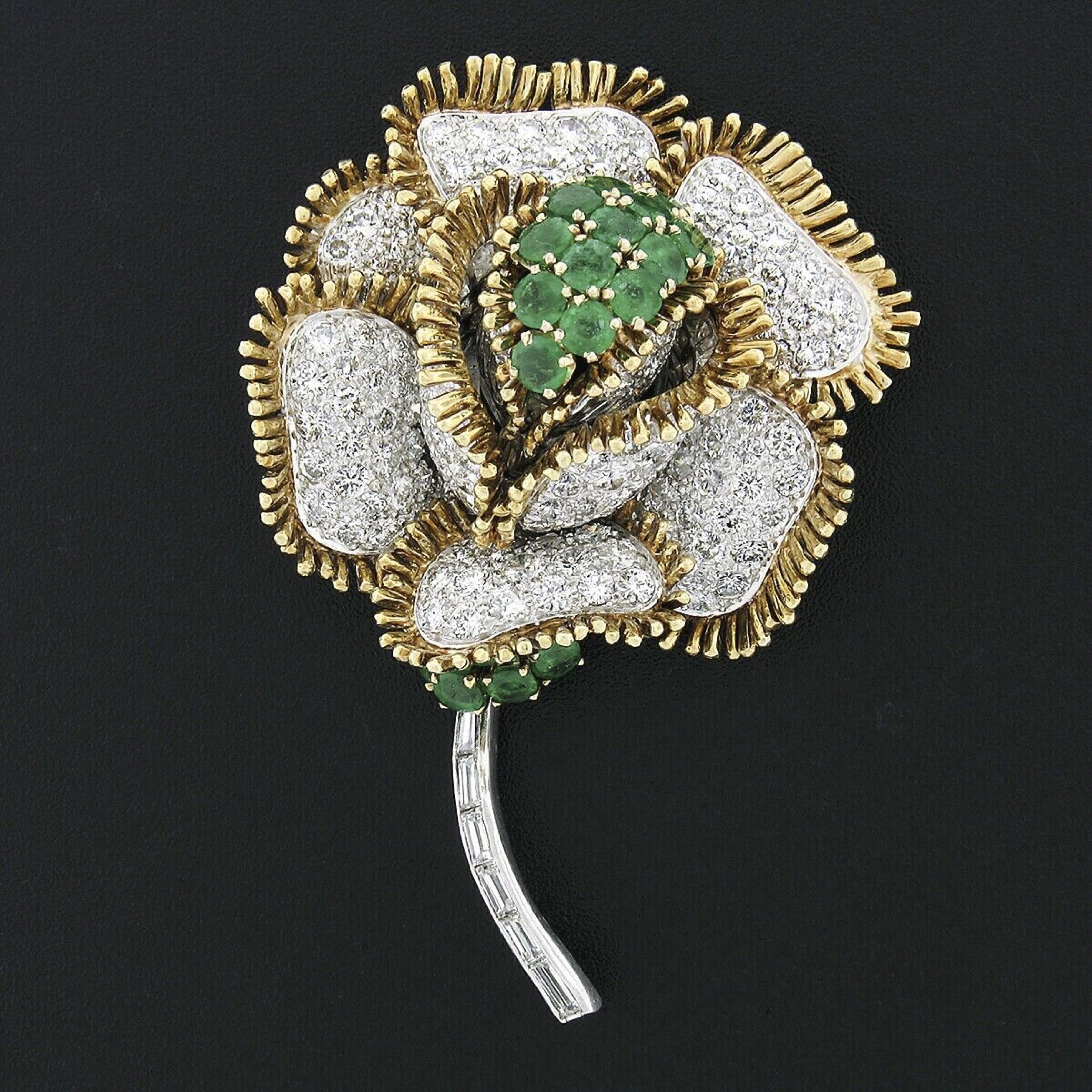 This superb vintage brooch is very well crafted in solid 18k gold and solid platinum and features a magnificent three-dimensional flower design that's completely covered with the finest quality diamonds and emeralds throughout. The stem and flower