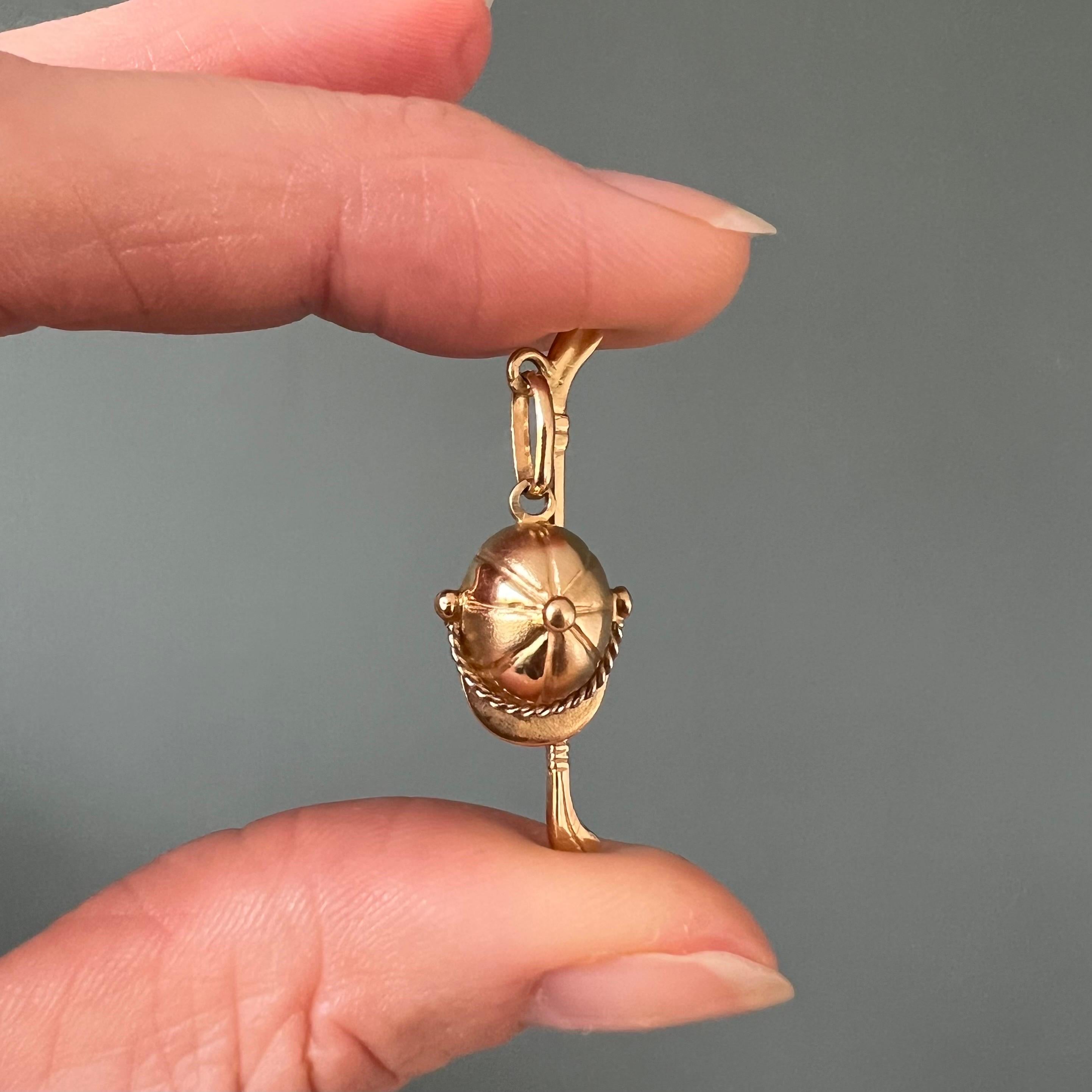 This is a vintage horse polo riders equipment charm pendant, consisting of a riding helmet and polo stick. The 18 karat yellow gold riders helmet and polo stick are beautifully crafted and detailed. The helmet has a rope band above the visor and