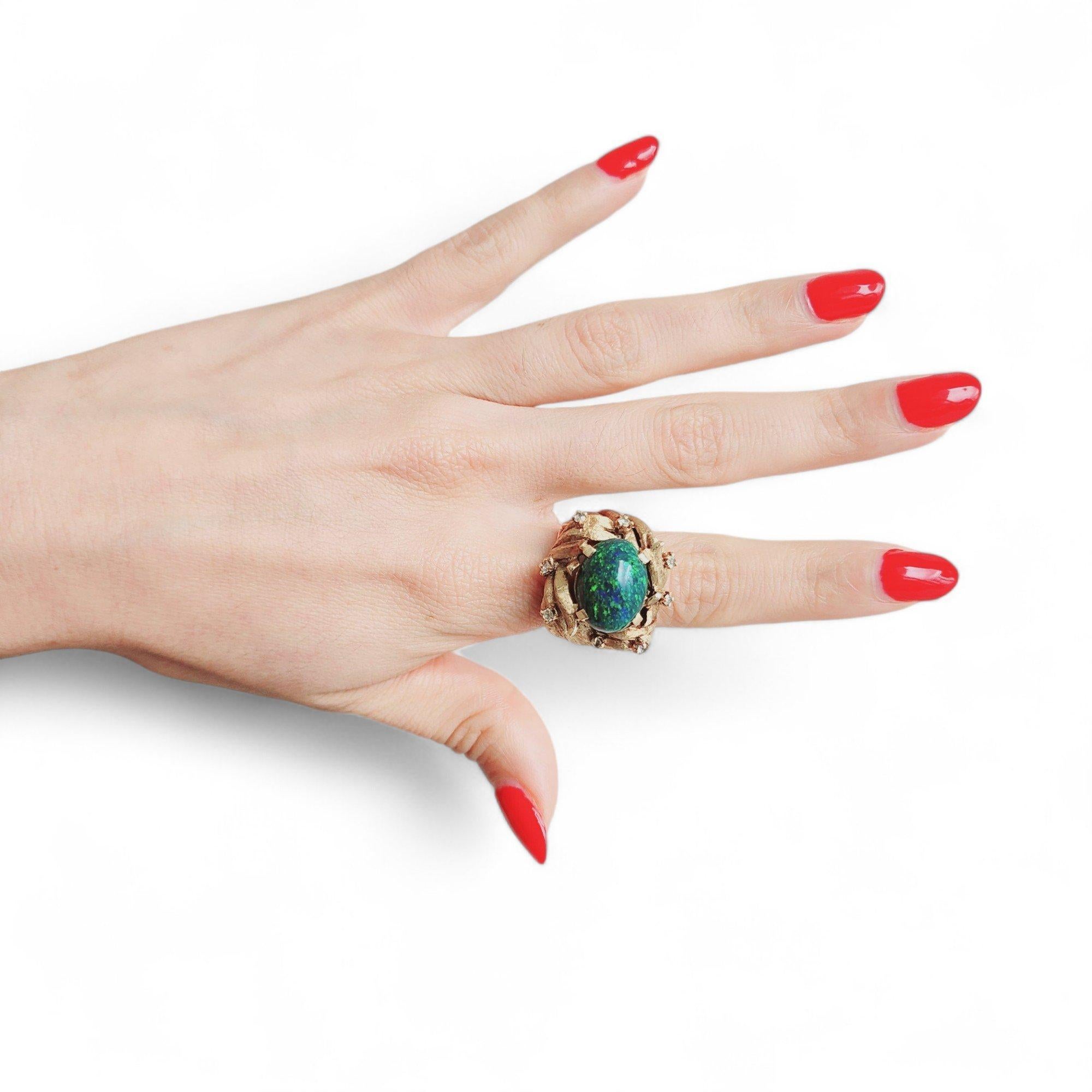 This gorgeous contemporary ring showcases the mesmerizing beauty of natural black opal, meticulously crafted in rich 18kt yellow gold and featuring a captivating 6.05-carat cabochon black natural opal as its stunning centerpiece, elegantly accented