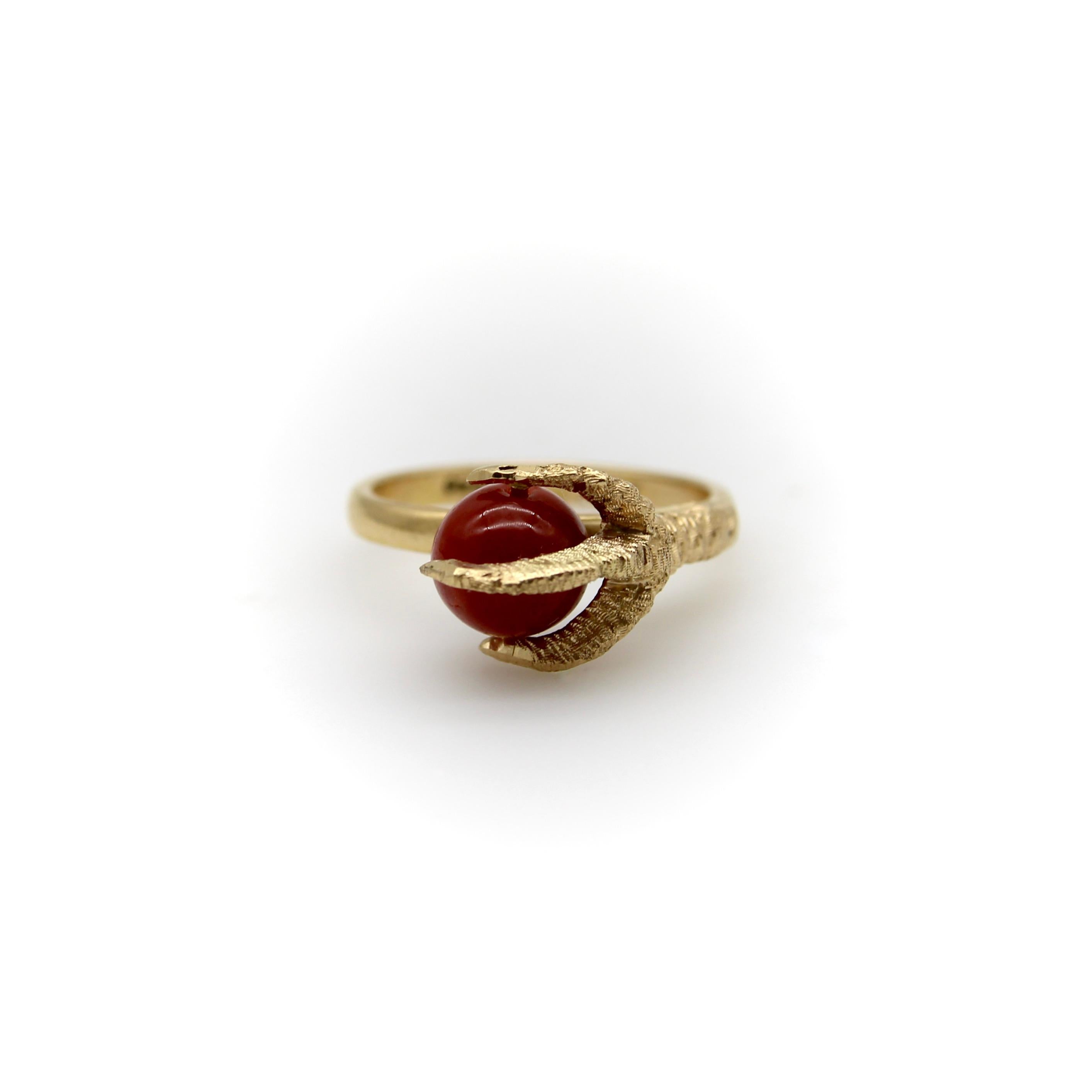 In questo anello vintage in oro 18k, un artiglio tridimensionale si alza e stringe una perla di corallo. L'artiglio è incredibilmente realistico, con una texture opaca e dettagli intricati. La perla è di un ricco rosso corallo sardo che risalta