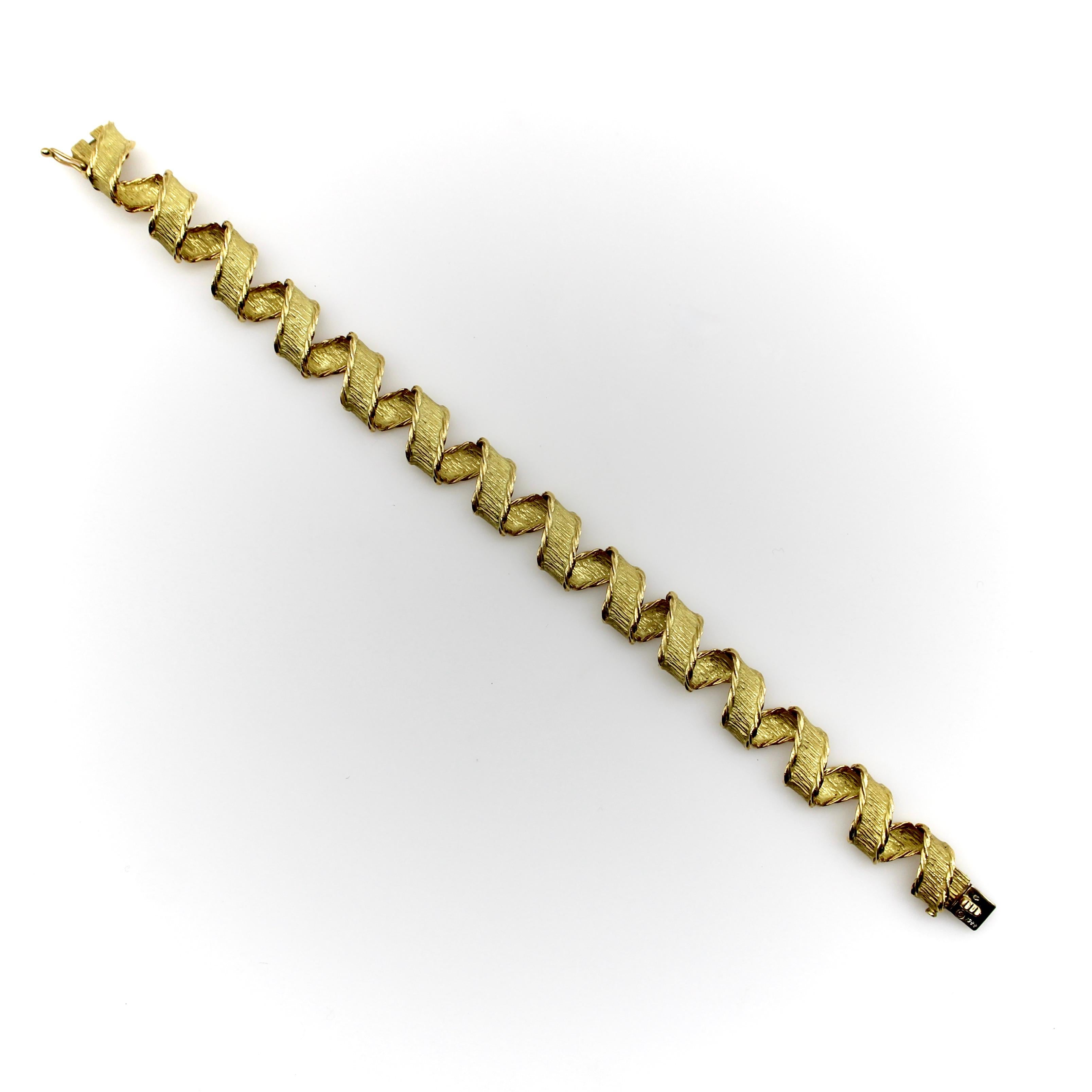 This 18k gold bracelet made by Tiffany & Co. in Paris, France exhibits exquisite craftsmanship. The design has an intricate link that, when put together in a repeating line, creates a three-dimensional ribbon out of gold that wraps around itself in