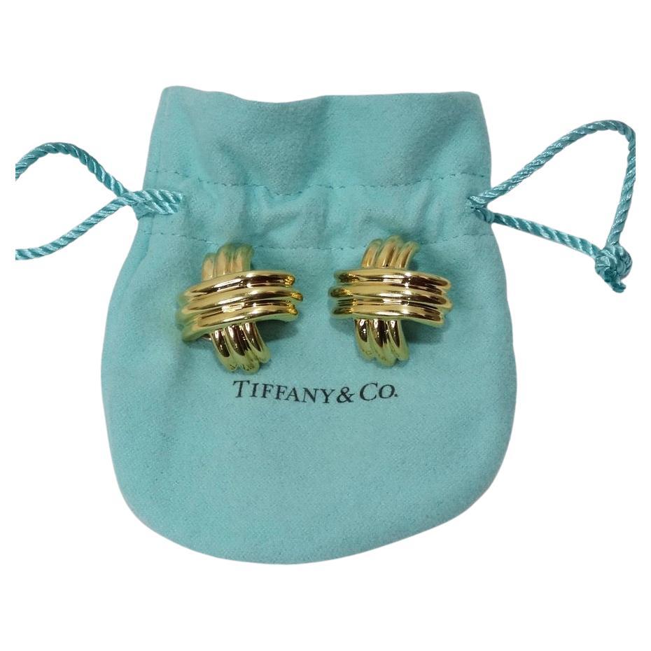 Gorgeous Tiffany & Co 18K gold clip on earrings. Large stud style in an 'X' shape with engraved detailing and omega backs. These earrings are a great essential for any occasion as they add the perfect pop of elegance to any look while still being