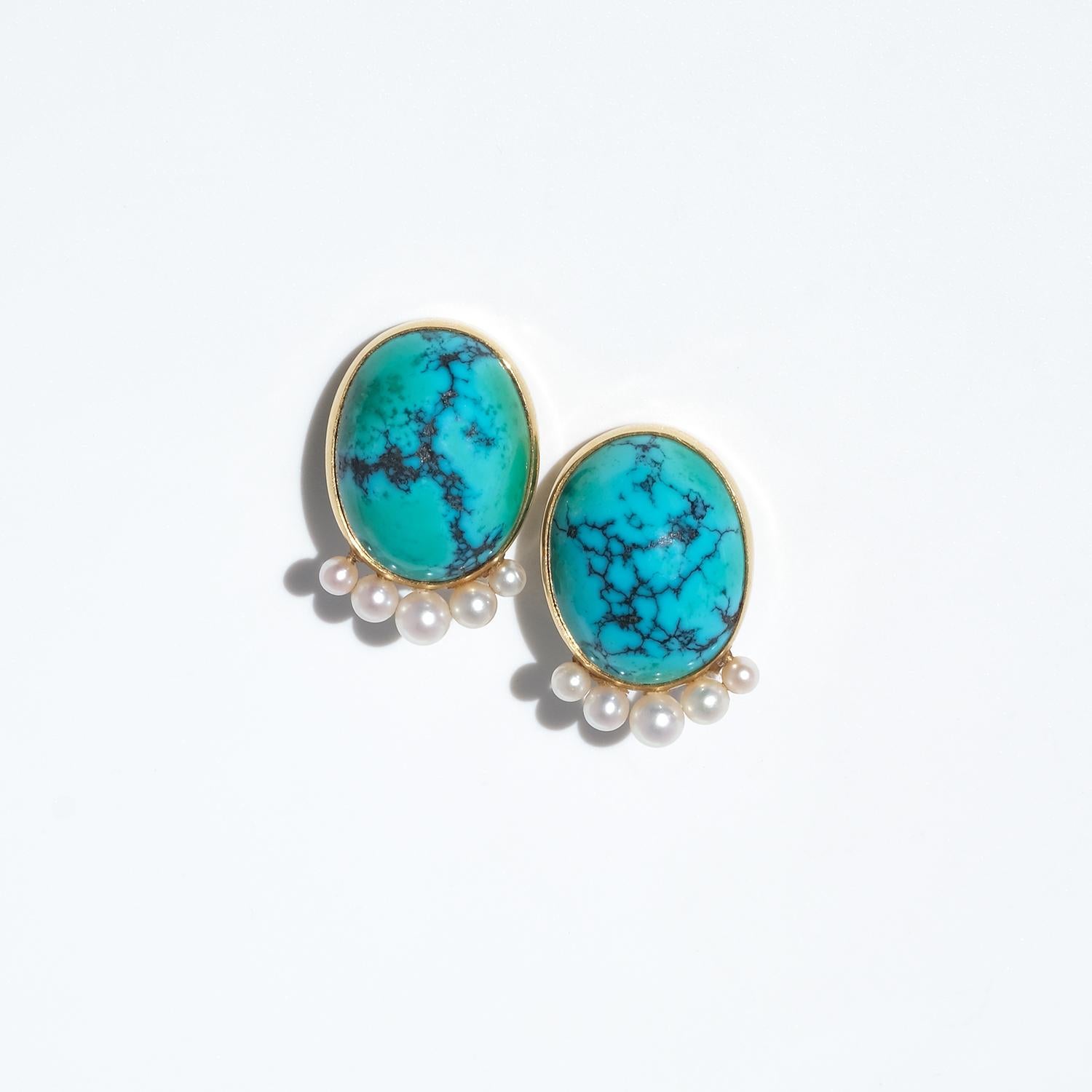 These vintage clip-on earrings, crafted in 18-karat gold, feature a bold yet elegant design. At the center of each earring sits an oval cabochon-cut turquoise with a smooth, polished surface, radiating a rich hue. Below the turquoise, five cultured