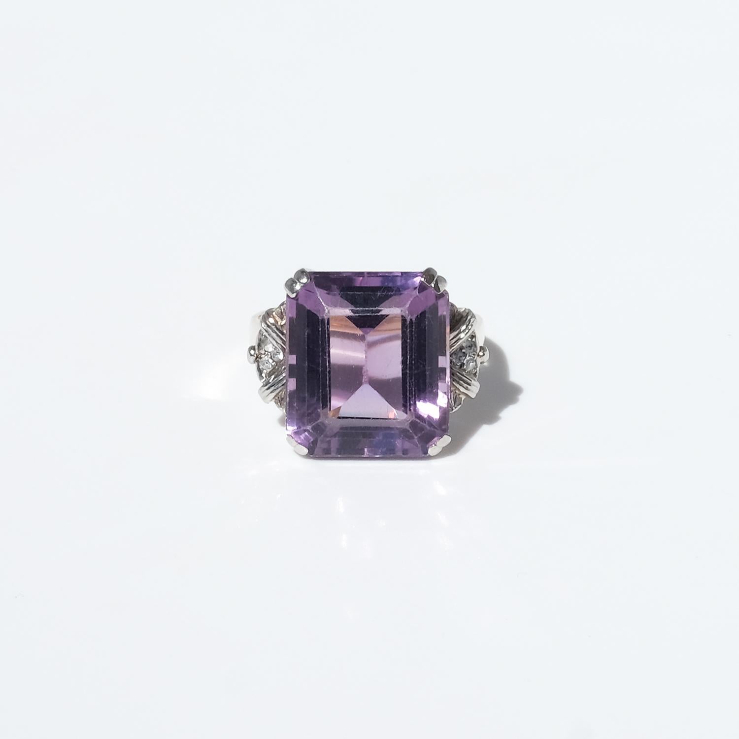 This exquisite ring is crafted with a combination of 18-karat white and red gold. The setting, crafted from white gold, securely holds a beautifully faceted amethyst, its deep purple hue shimmering with every movement. Surrounding the setting, three
