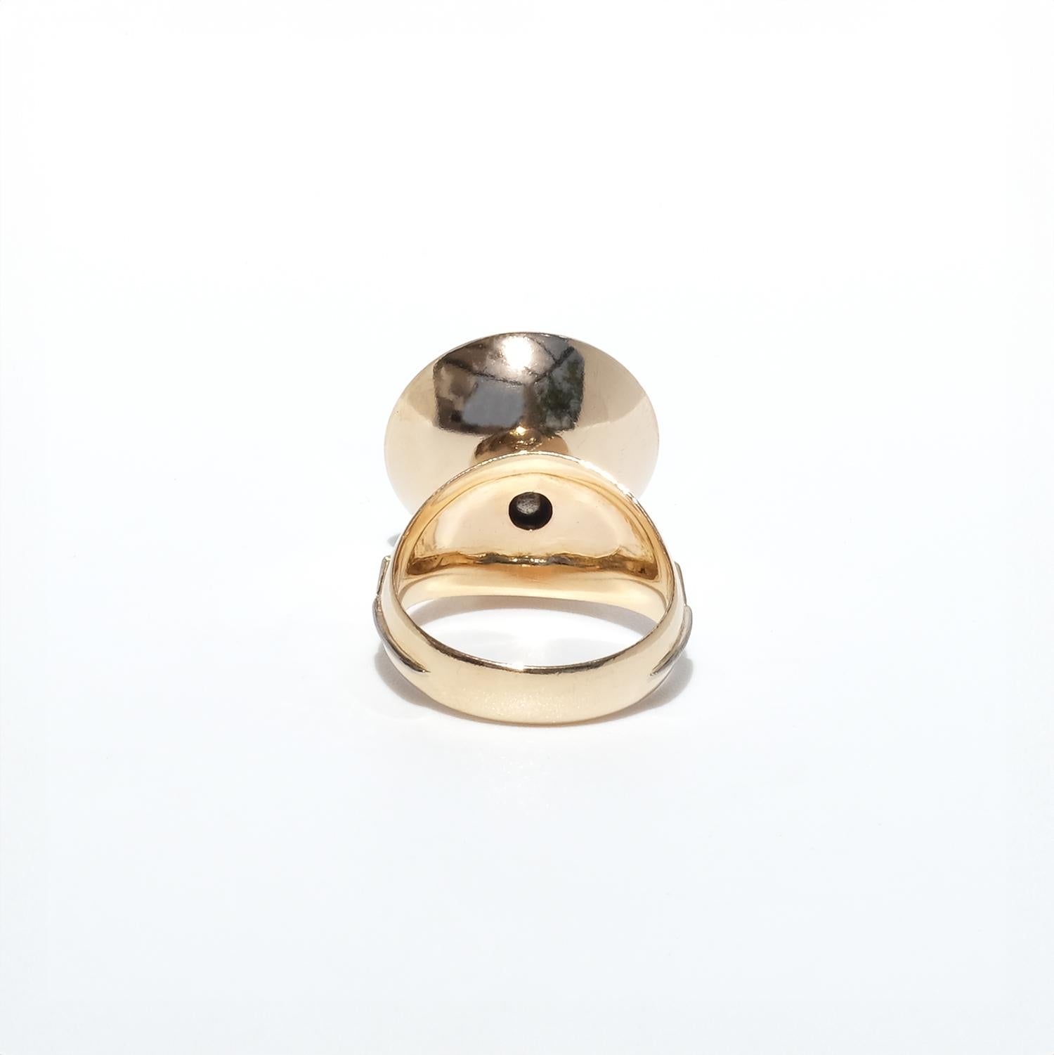 This 18-karat gold and white gold vintage ring features a mabe pearl with a smooth, domed surface, embraced by a bowl-like setting. The ring's shank widens as it approaches the setting, creating an elegant neck with patterned engravings. White gold