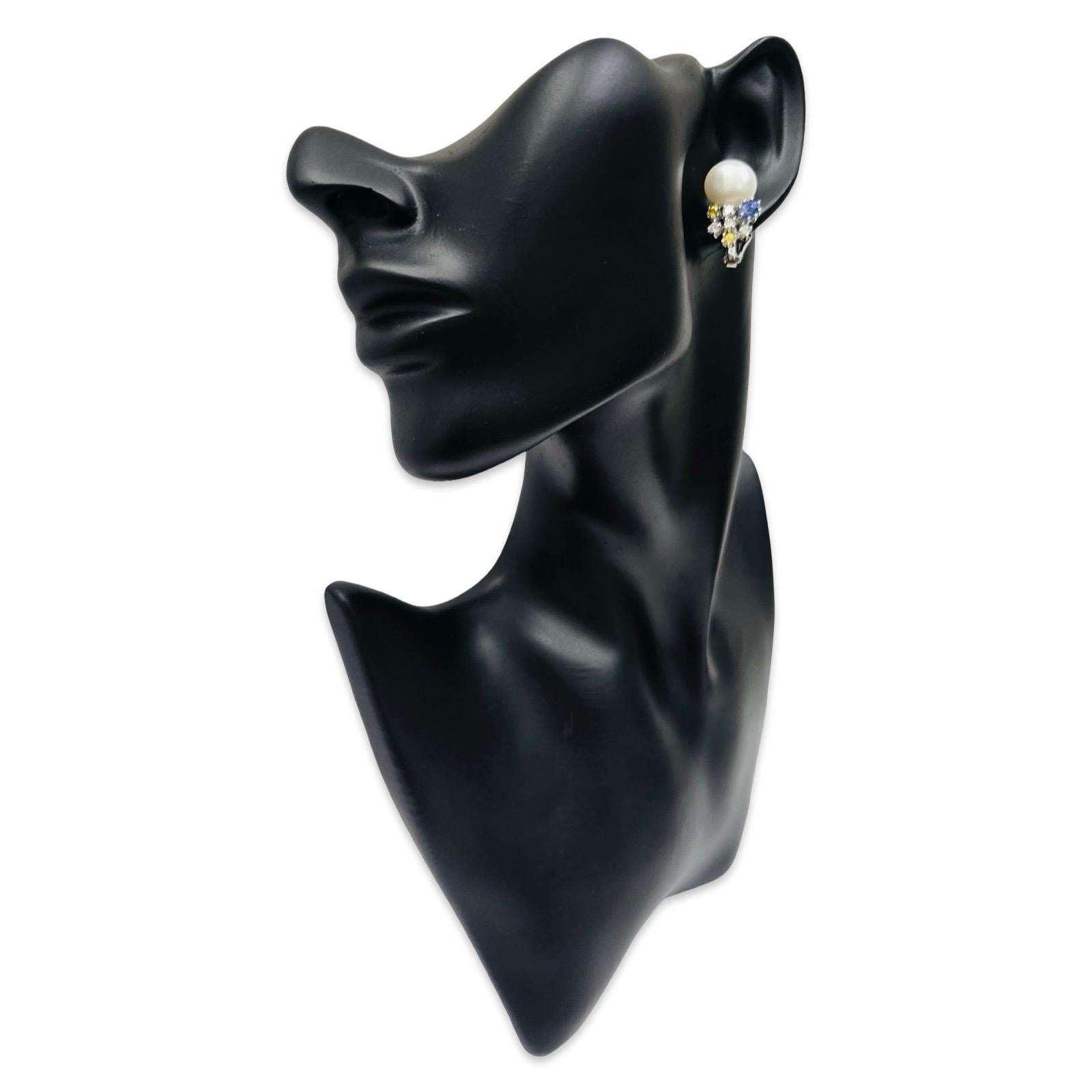 Questi raffinati orecchini vintage sono realizzati in oro bianco massiccio 18 carati e presentano perle coltivate di 12,15 mm con una superficie luminosa e a specchio. Sotto ogni perla si trova un grappolo di gemme pregiate in stile costellazione,