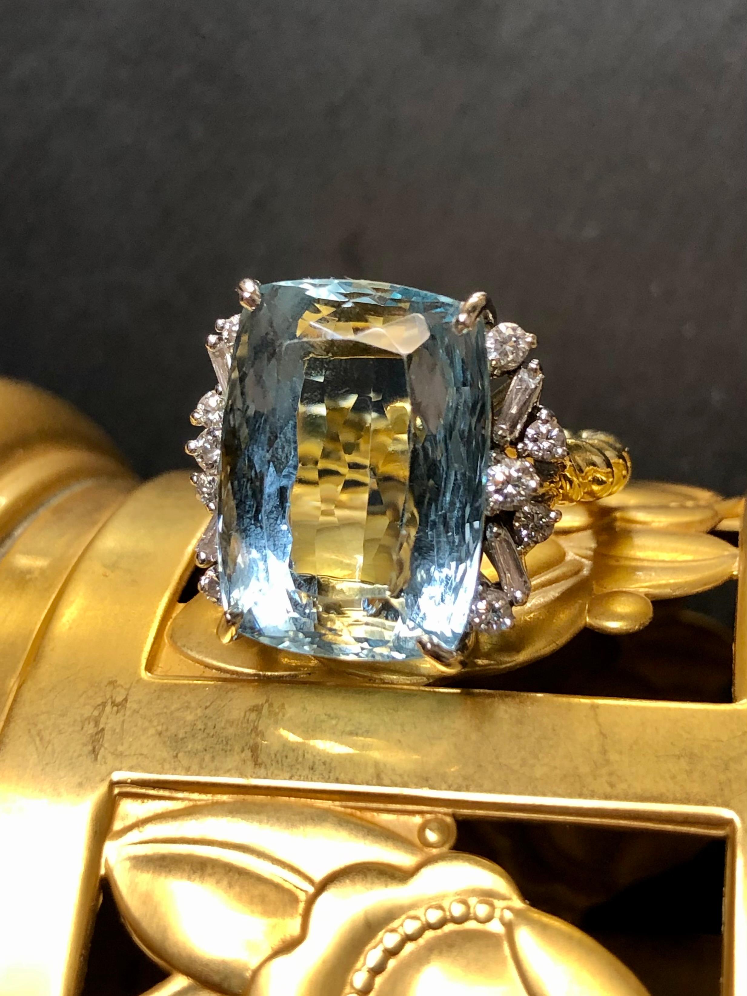 A stunner of a ring c. the 1960’s done in 18K yellow and white gold centered by an approximately 15.50ct natural, elongated cushion cut aquamarine flanked by approximately .70cttw in tapered baguette and round cut diamonds averaging G-H color and