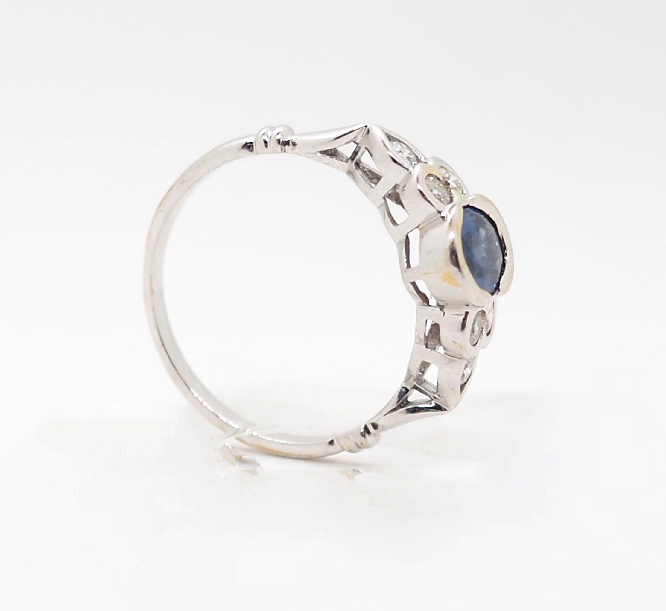Gönnen Sie sich zeitlosen Luxus mit unserem exquisiten Vintage-Ring, der aus glänzendem 18-karätigem Weißgold gefertigt und mit einem bezaubernden ovalen Saphir geschmückt ist, der von drei schillernden Diamanten auf jeder Seite flankiert wird, die