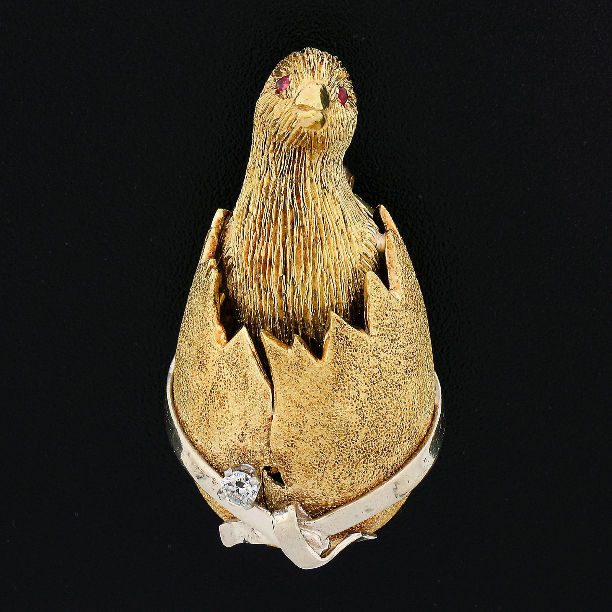 This wonderful and very well made pin/brooch features an incredibly well detailed design of a cute chick breaking out of an egg. The chick's eyes are set with vivid red rubies while the egg is wrapped with a white gold ribbon and a natural brilliant