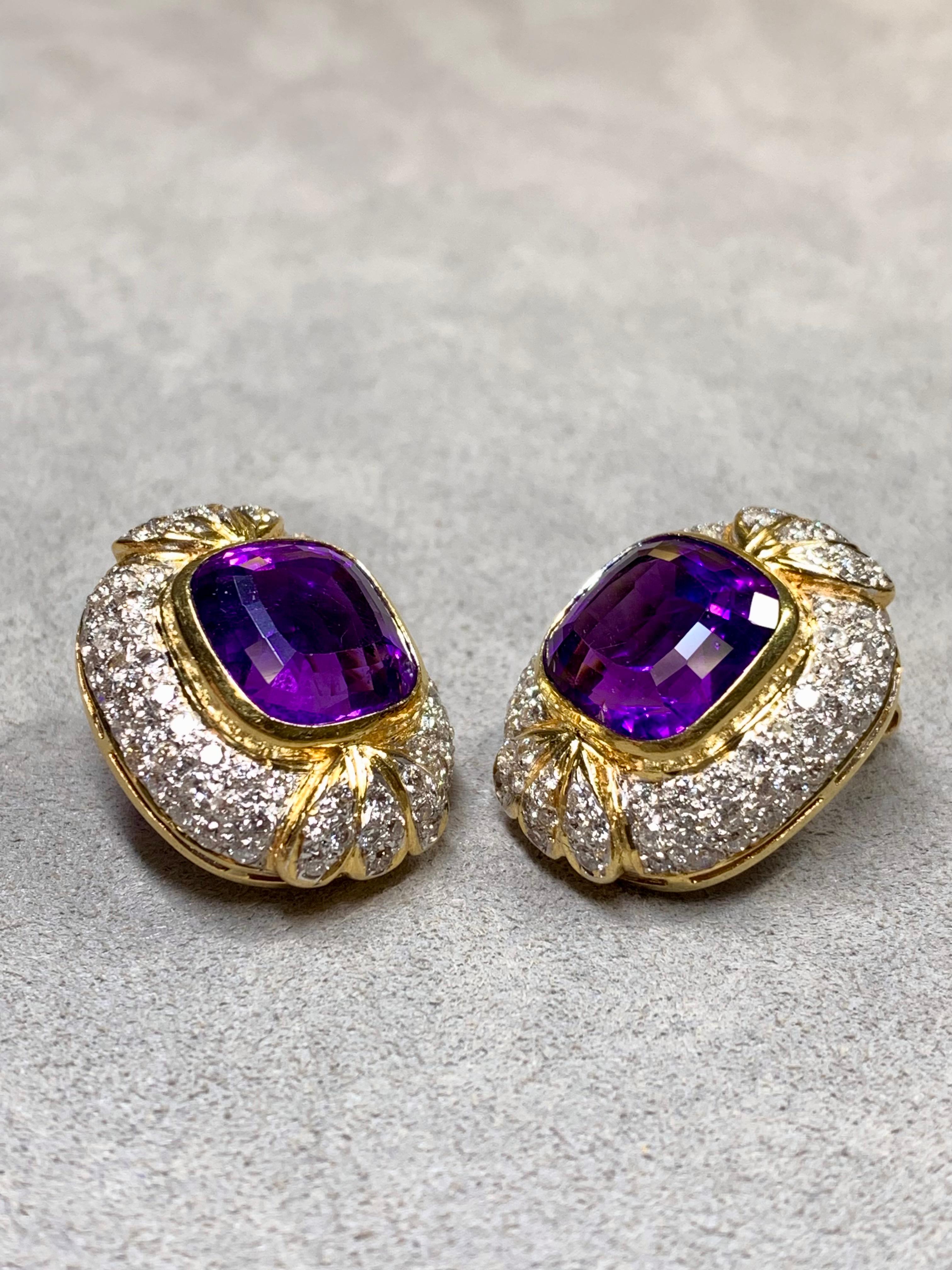 A STUNNING pair of huggies done in 18K yellow and white gold, centered by two cushion shaped natural amethysts weighing approximately 15ctw combined. Surrounding the Centerstone is approximately 3.20ctw in H-I color Vs2-Si1 clarity rounds