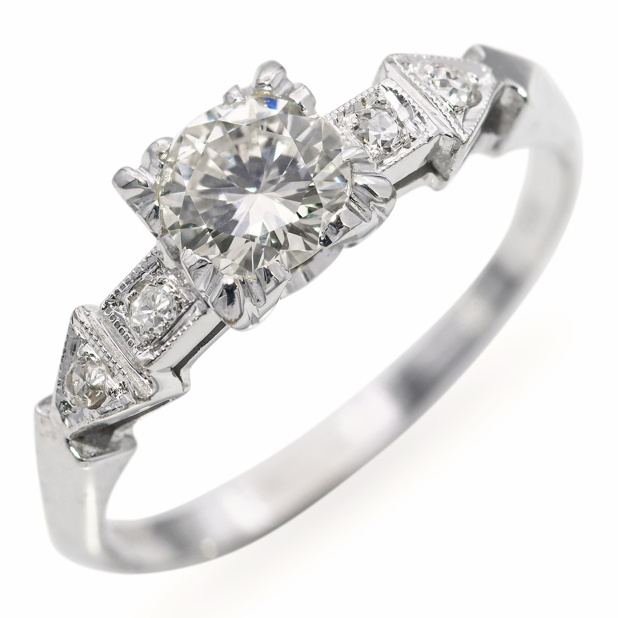 Élégante et intemporelle, cette bague de fiançailles vintage est réalisée en or blanc 18 carats lumineux et sertie d'environ 0,52 carats de diamants étincelants. Le design présente un diamant central taillé en brillant, accentué par des pierres plus