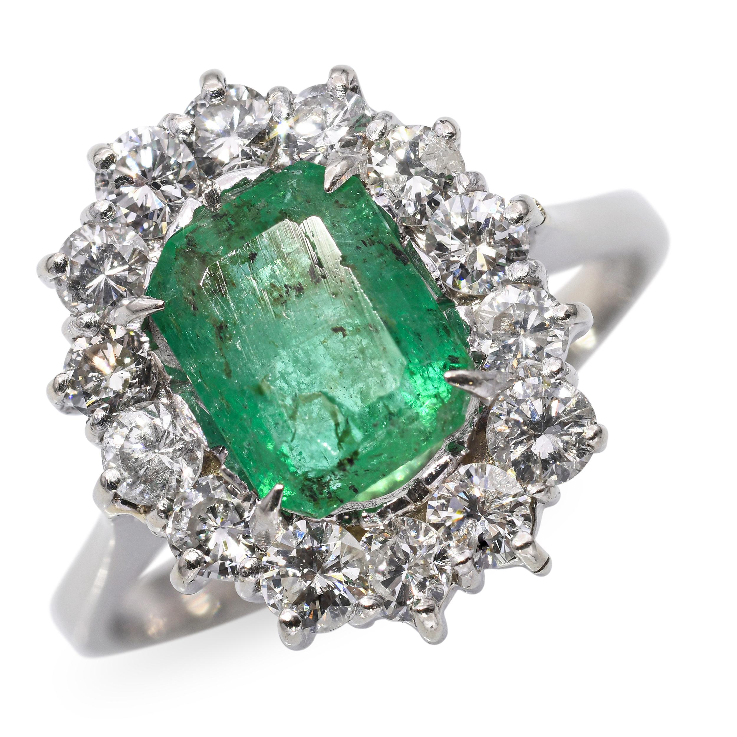 Cette élégante bague vintage présente une émeraude naturelle de 1,49 carat sertie dans de l'or blanc 18 carats, encadrée d'un halo étincelant de diamants totalisant environ 0,42 carat. L'émeraude est richement saturée, offrant une teinte verte