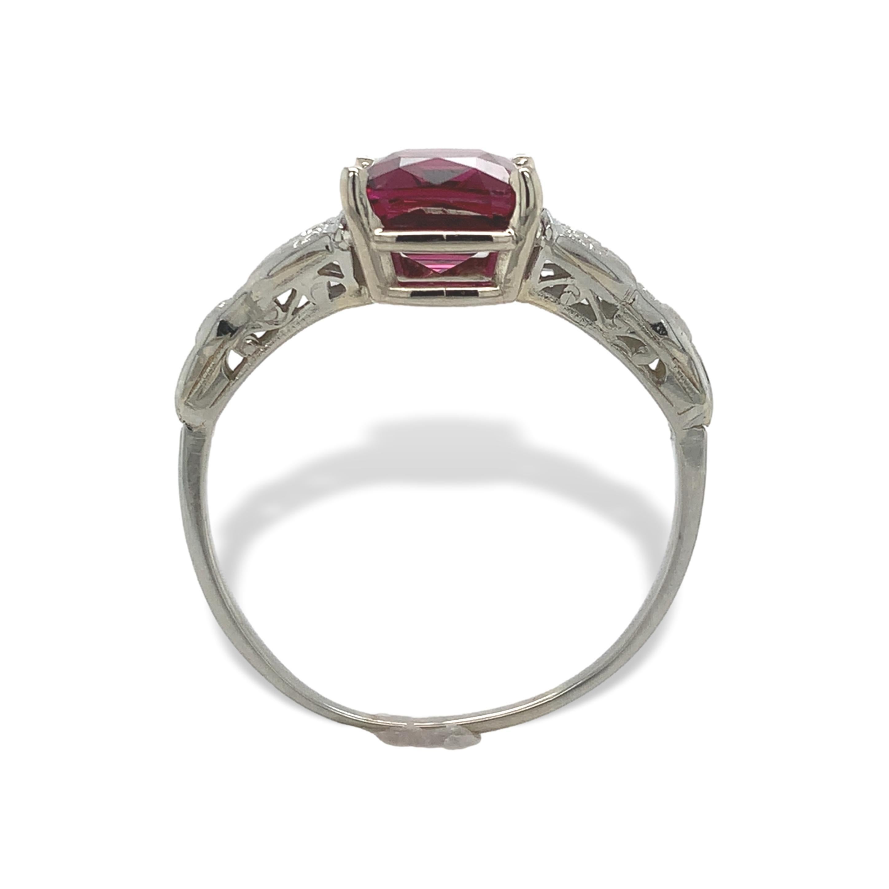 18K white gold ring set with an antique cushion cut garnet weighing 3.02 carats. The very pretty raspberry colored garnet measures about 9mm x 7.5mm. The setting has hand engraved design and filigree with a new head. The ring fits a size 8.5 finger,