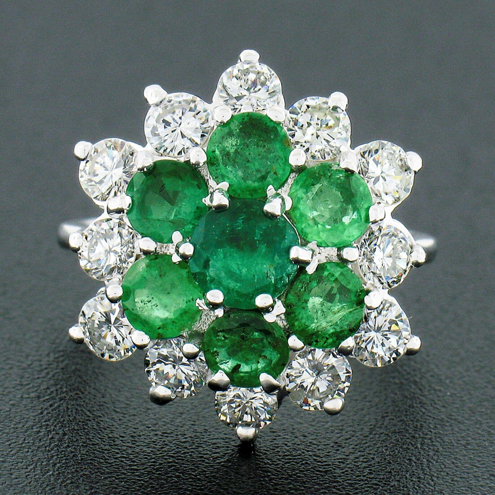 Here we have a large, vintage, diamond and emerald cluster flower ring crafted in solid 18k white gold and featuring a cluster of 7 round emeralds surrounded by a set of 12 round brilliant cut diamonds. The diamonds weigh an approximate total of