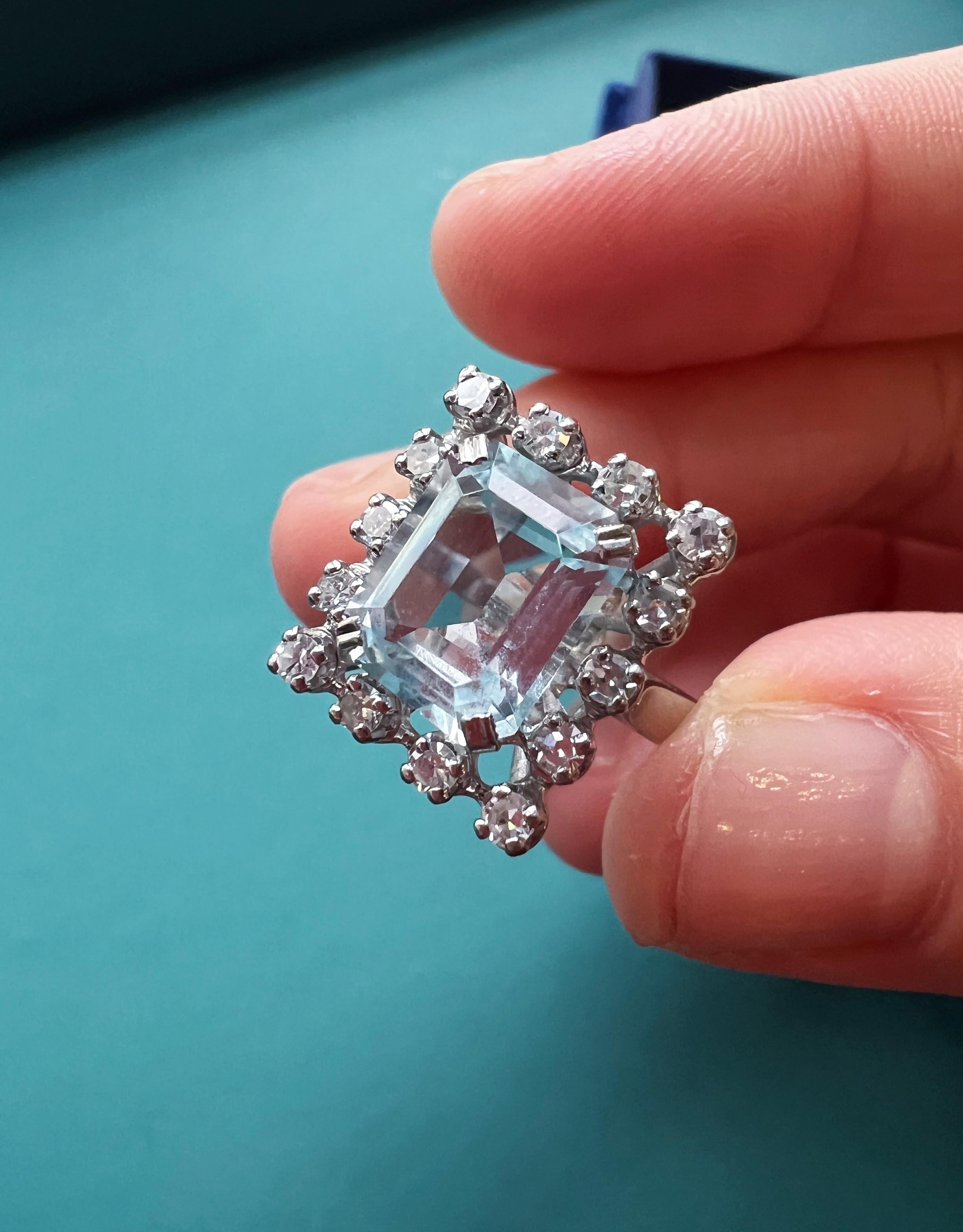For sale a beautiful French work, aquamarine and diamond cocktail ring in cluster setting style.

The central eye-clean aquamarine is emerald cut and prong set. It conveys the famous pastel, cooling blue color of the aquamarine and it weights