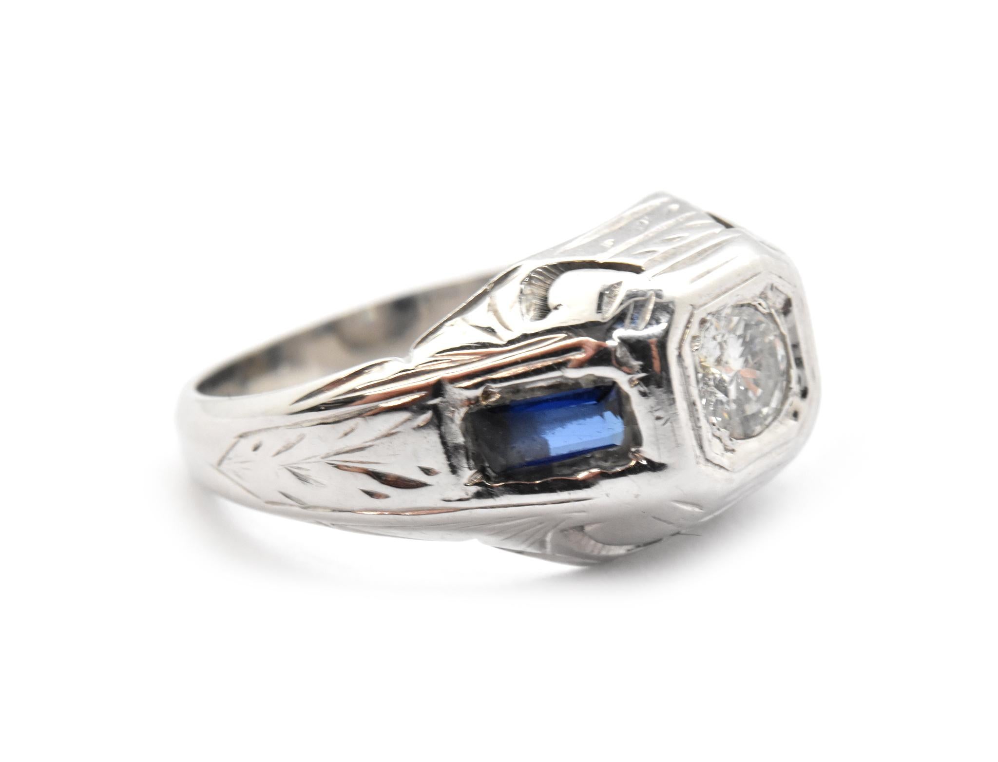 This lovely vintage ring is made in 18k white gold, and it holds a 0.12ct round brilliant cut diamond at its center. The diamond is graded G-H in color and SI1 in clarity.  There are two 4x2mm baguette blue sapphires set on either side. The ring