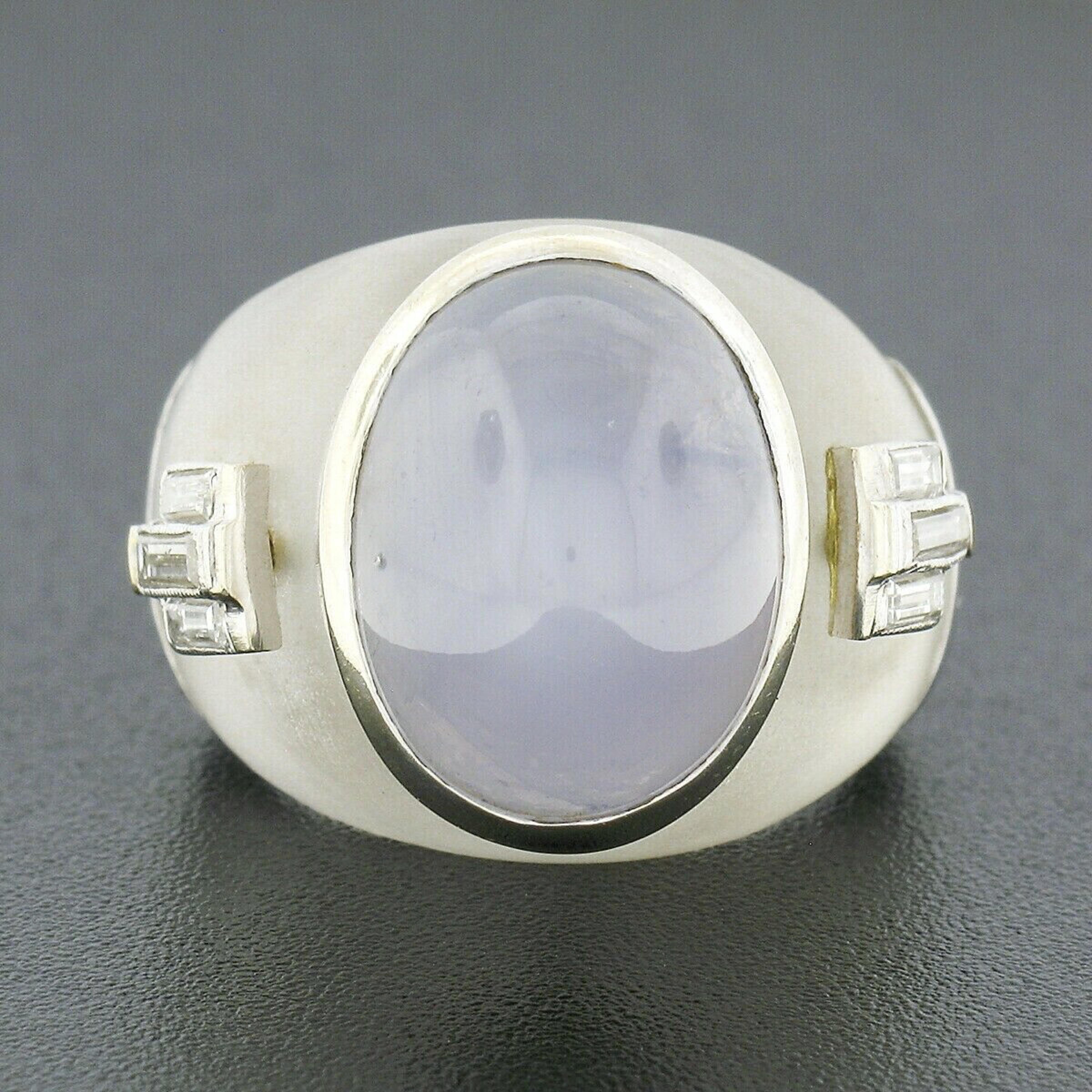 This large vintage statement ring is crafted in solid 18k white gold and features a magnificent, oval cabochon natural star sapphire bezel set at its center. The sapphire has rich and attractive and desirable gray-blue color with a well centered,