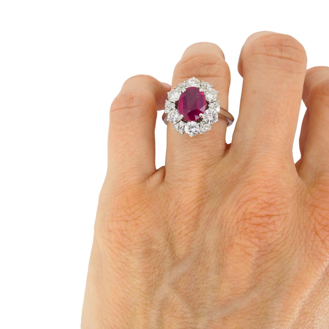 Dieser Vintage-Ring aus 18 Karat Weißgold ist mit einem 1,75-kar�ätigen natürlichen Rubin burmesischen Ursprungs besetzt. Der Rubin im Ovalschliff wird von einem Halo aus leuchtenden Diamanten im Rundschliff eingerahmt. Mit seinen ausgewogenen