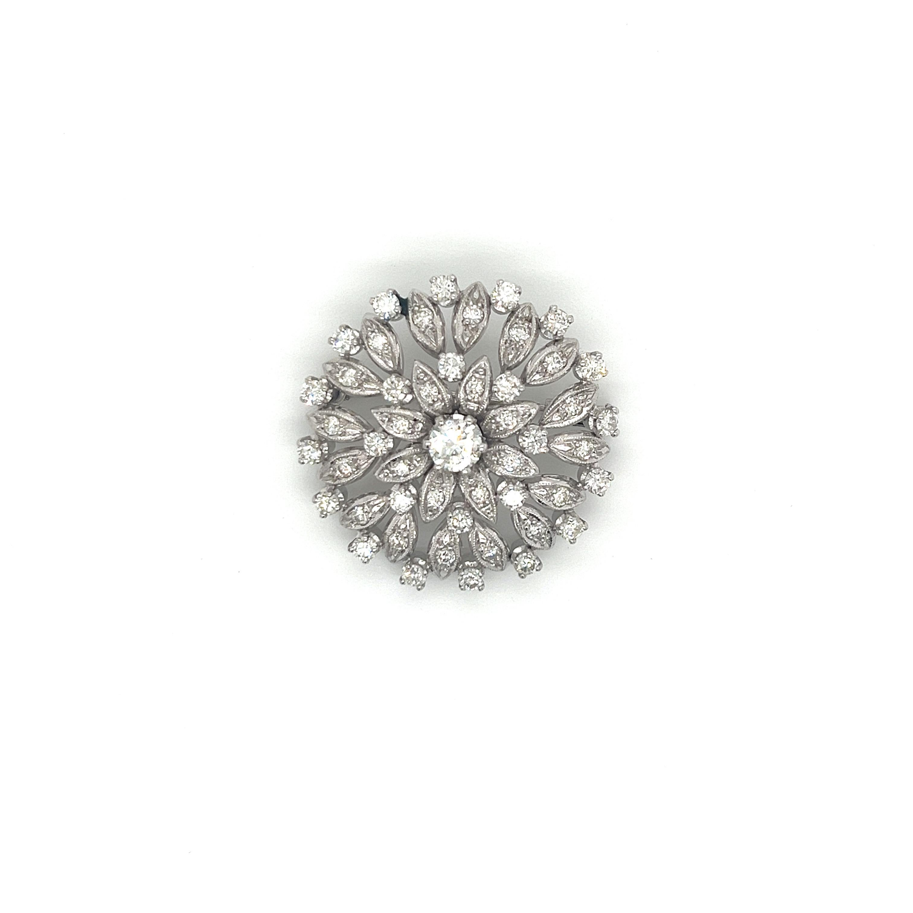 This exquisite vintage brooch from the 1960s is a true representation of timeless elegance. Crafted in luxurious 18k white gold, the piece showcases a breathtaking floral design adorned with dazzling diamonds.

At the heart of this brooch sits a