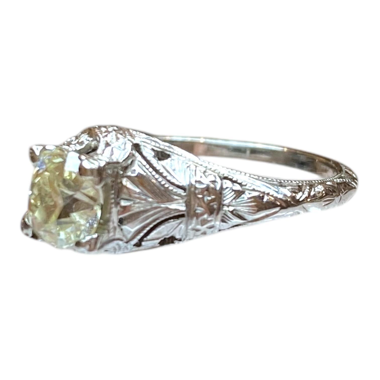 Vintage 18K white gold Art Deco style engagement ring, featuring an old mine cut diamond solitaire. The diamond is set in an intricately detailed mounting with delicate engravings and open work design.
Diamond: 0.85ct. Clarity: (VS1), Color: N (The