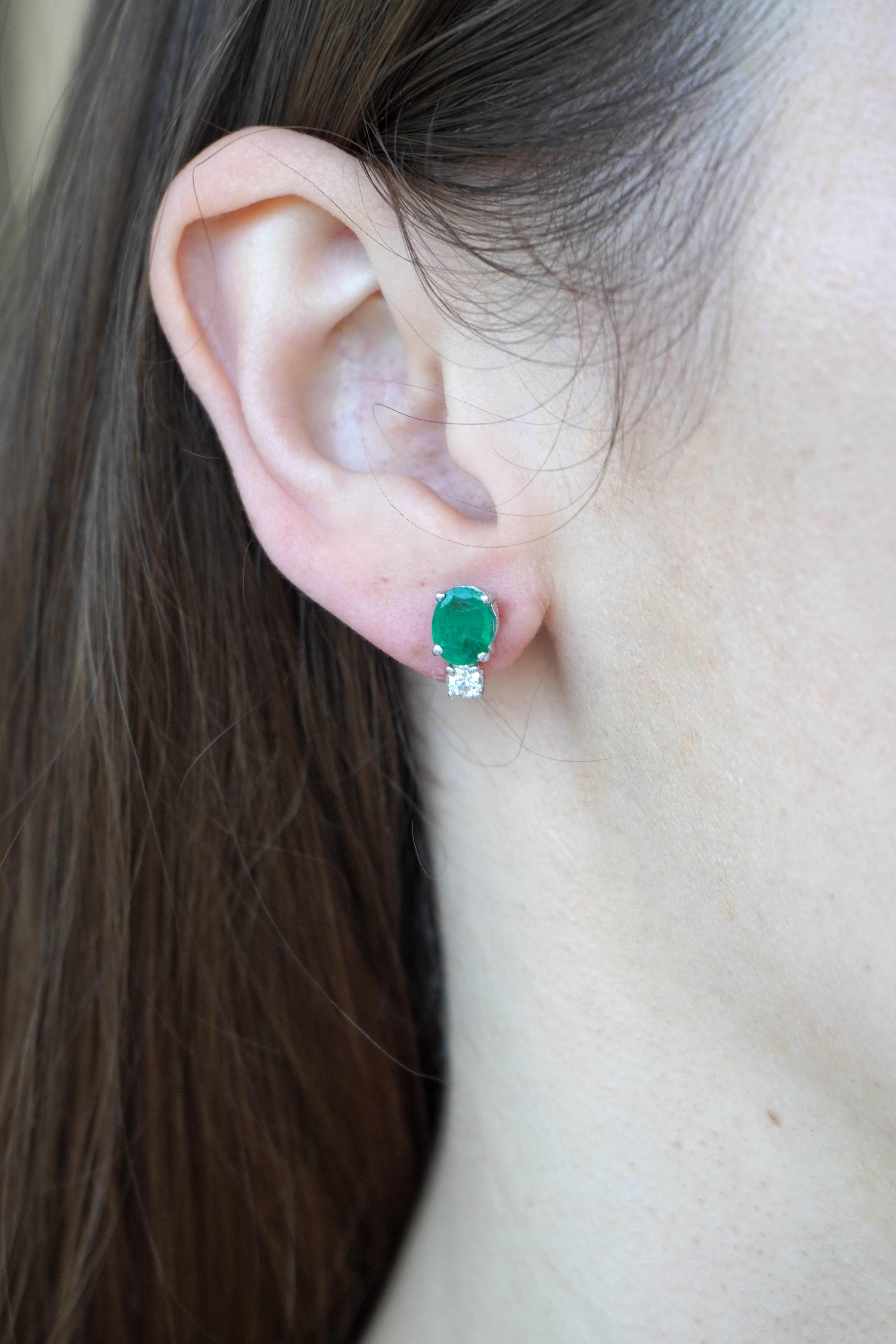 Este par de pendientes vintage de oro blanco de 18 quilates presenta una elegante combinación de esmeraldas y diamantes. Cada pendiente está diseñado con una esmeralda de talla oval situada sobre un diamante redondo de talla brillante, ofreciendo